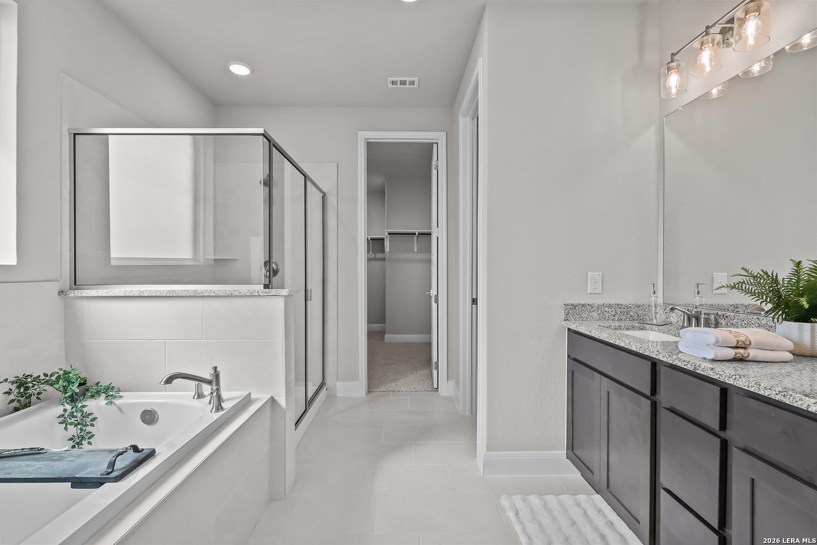 Elegant master bathroom featuring freestanding tub, glass shower, double vanity with granite in Davidson Homes The Rockford G, Ladera, San Antonio