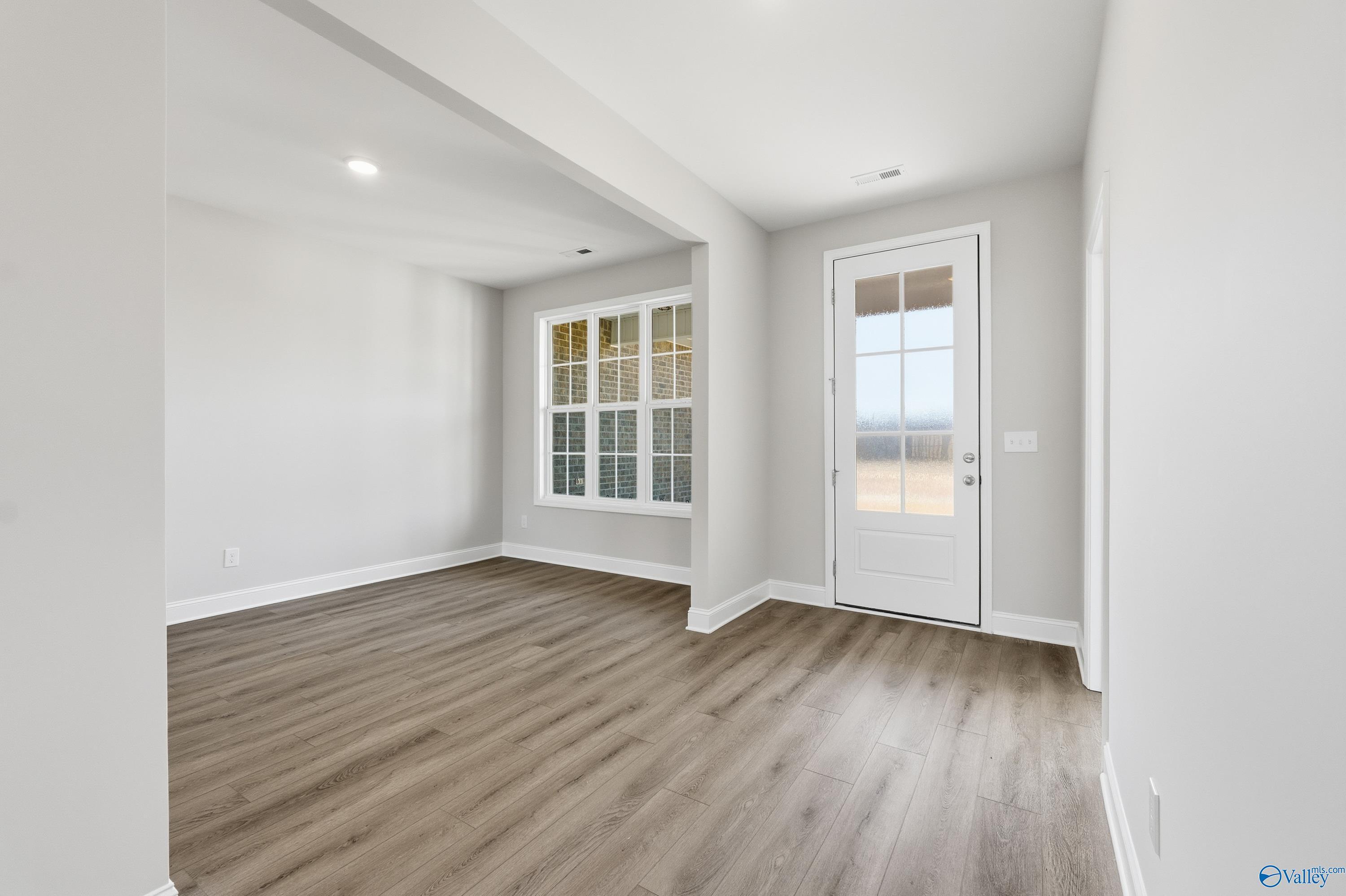 Spacious entry foyer with hardwood floors, large windows, and arched opening in Davidson Homes The Finleigh, Harvest AL