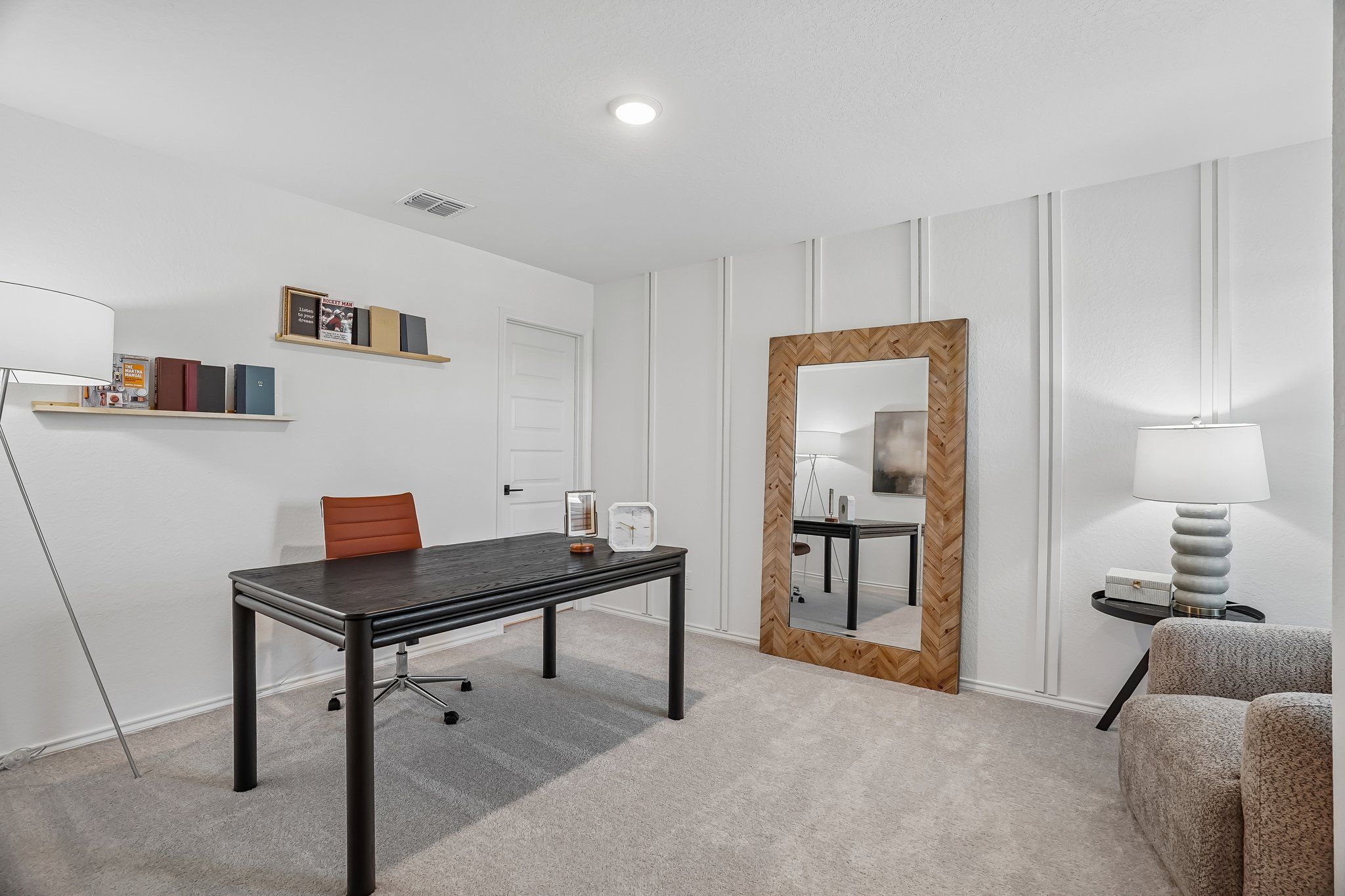 Modern home office at Fairway Crossing in Converse, TX featuring black desk, herringbone mirror, and board-and-batten walls.