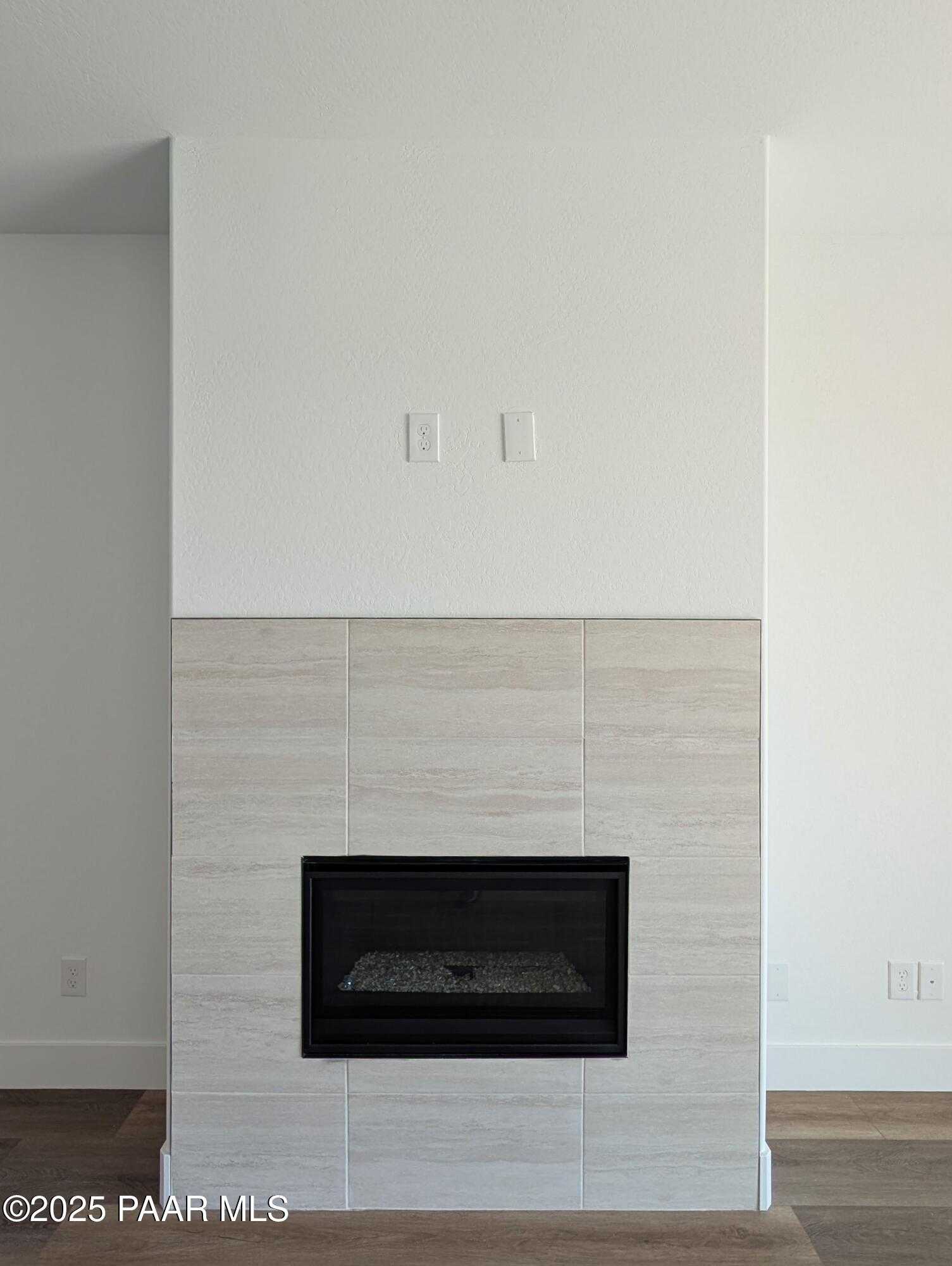 Modern gas fireplace with light neutral tile surround and hardwood floors in The Sheridan II F, Prescott, Arizona
