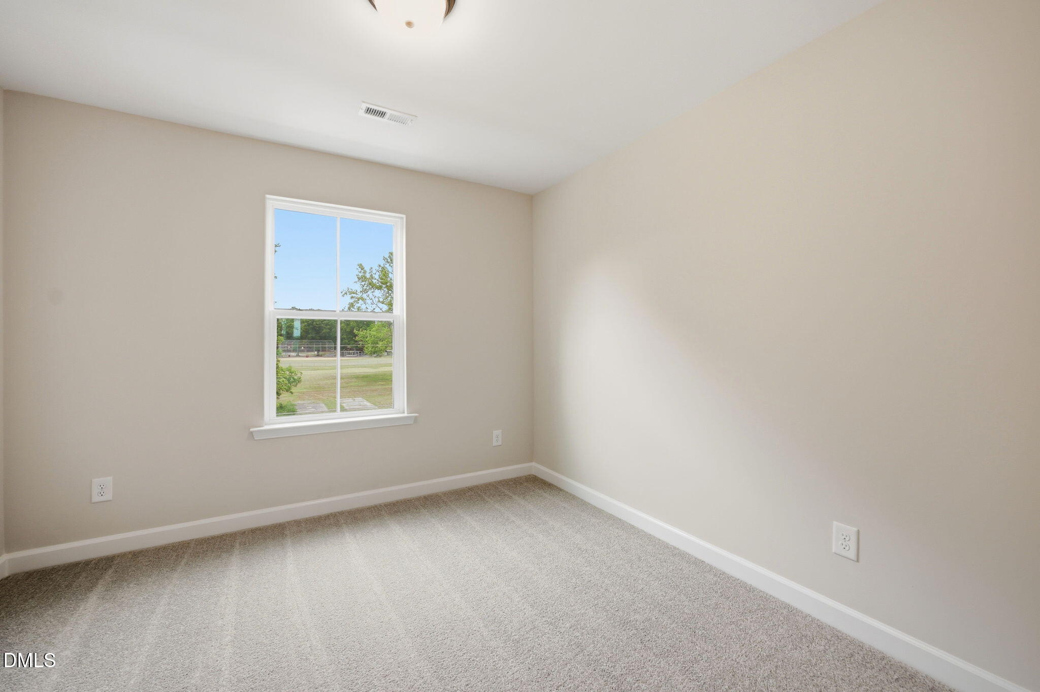 Bright, carpeted bedroom with neutral walls in The Mitchell floor plan at Camden Park, Knightdale, North Carolina.
