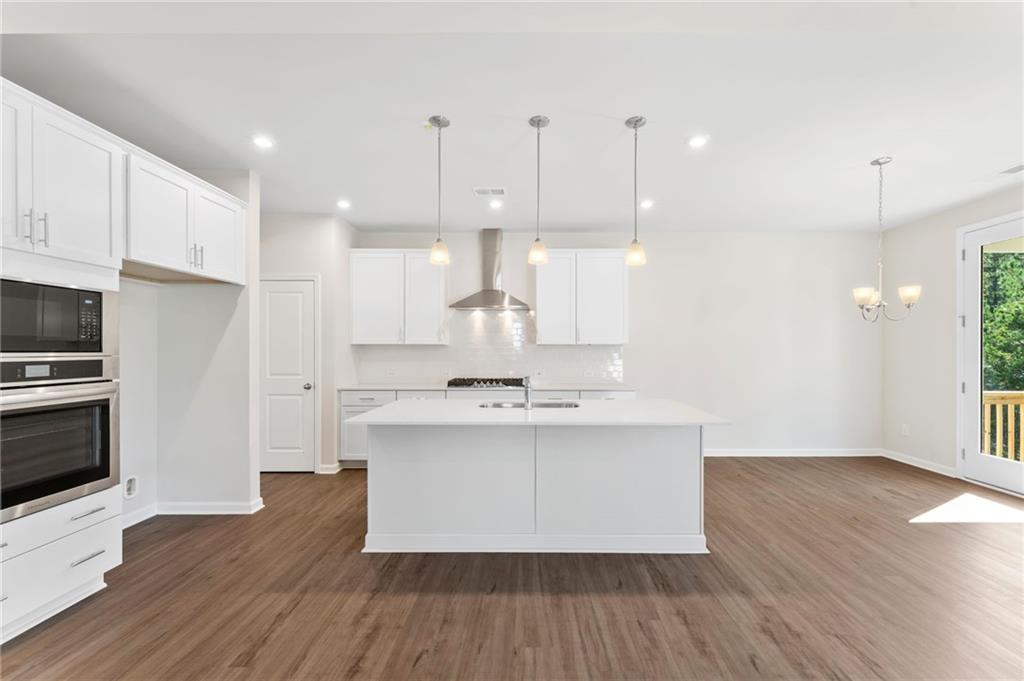 Modern open-concept kitchen with white island, stainless appliances in The Willow B by Davidson Homes, Dallas, Georgia