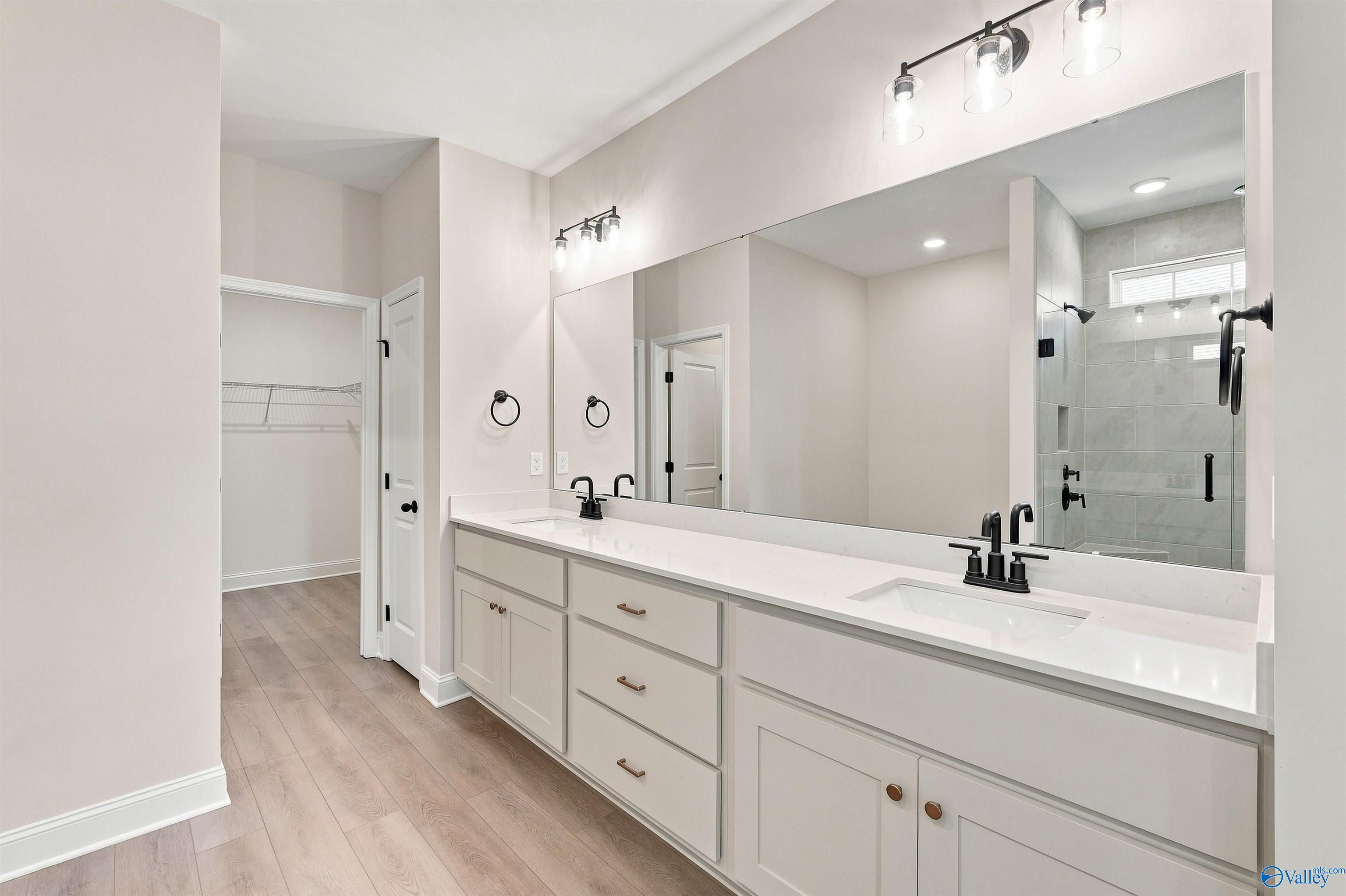 Modern primary bathroom with double vanity, quartz countertops, and walk-in shower in The Oxford, Kendall Farms, Toney, AL.