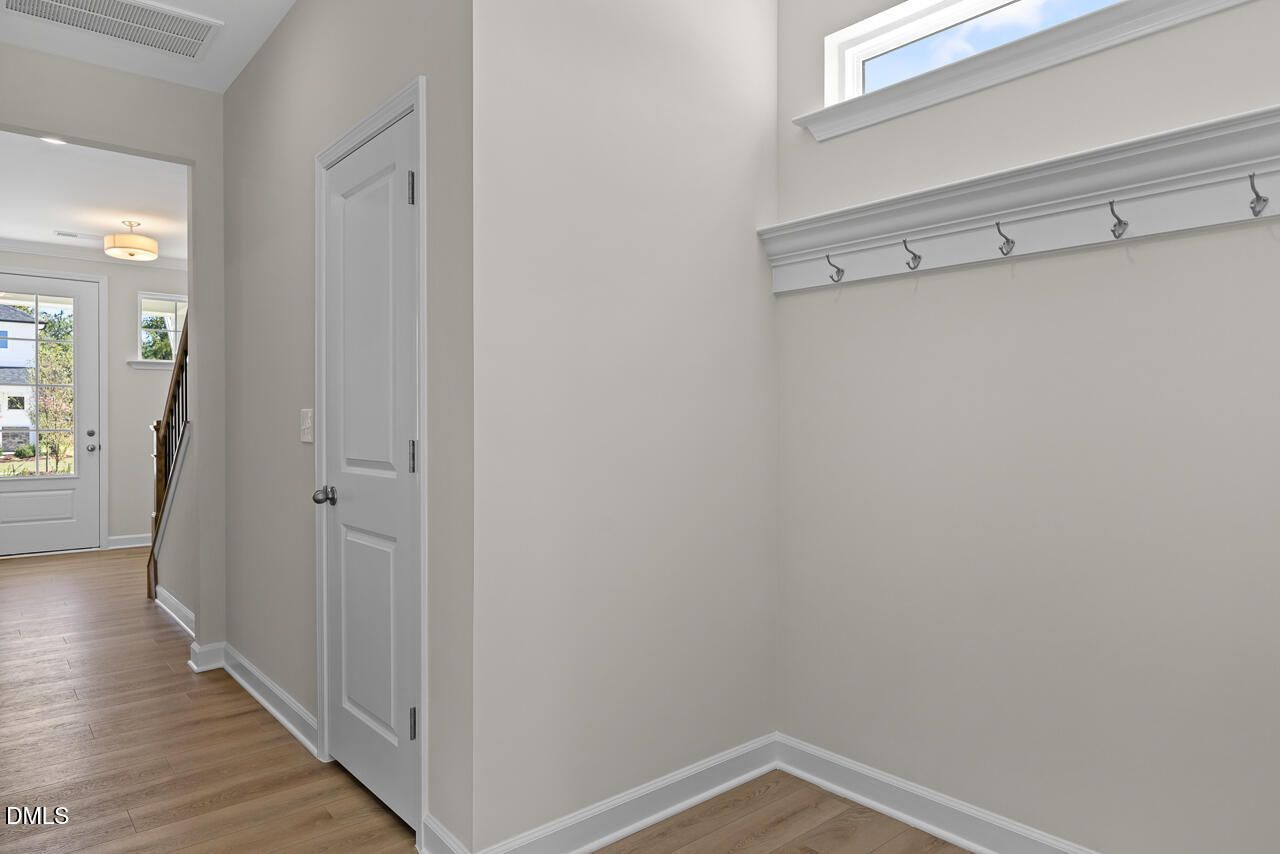 Mudroom with coat hooks, transom window, and hardwood floors in Davidson Homes The Preston B, Wendell Ridge, NC