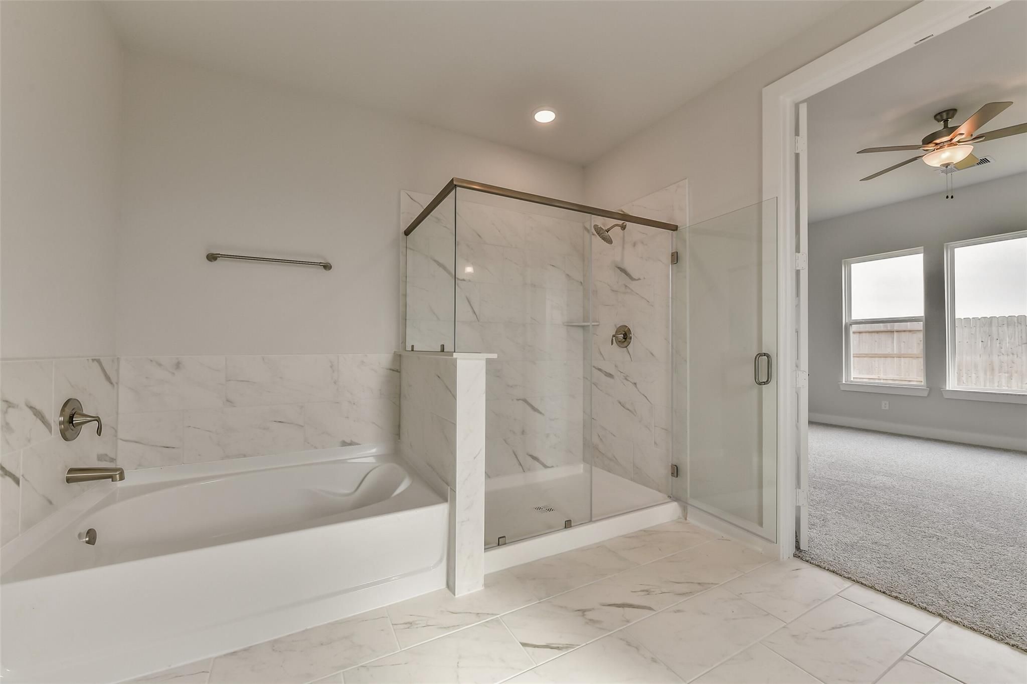 Luxurious master bathroom with frameless glass shower, freestanding tub, and white tile in Davidson Homes The George A, Lago Mar, Texas City
