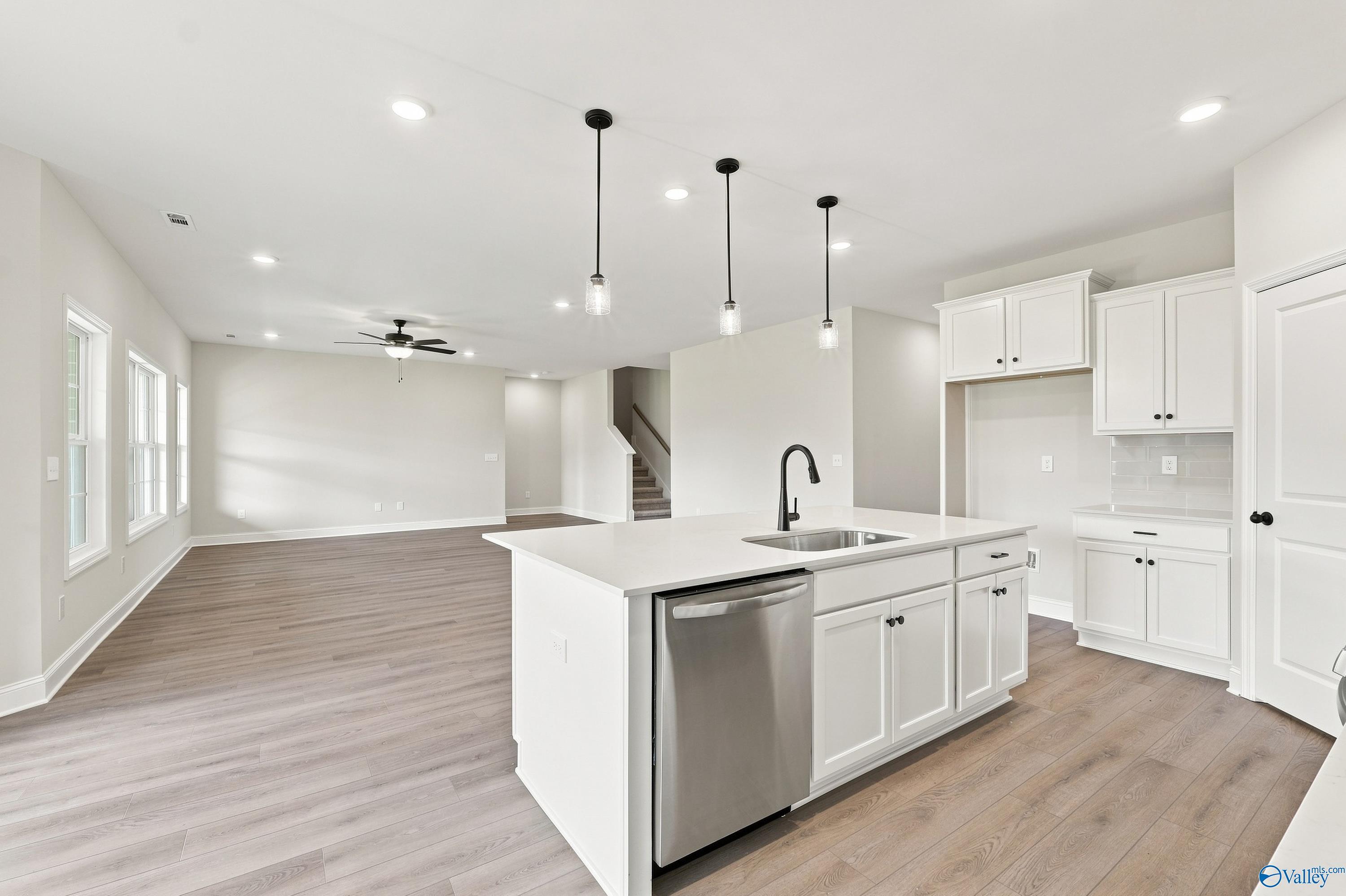 Open-concept kitchen with white cabinets and island in The Rockford B floor plan at Kendall Downs, Toney, Alabama.