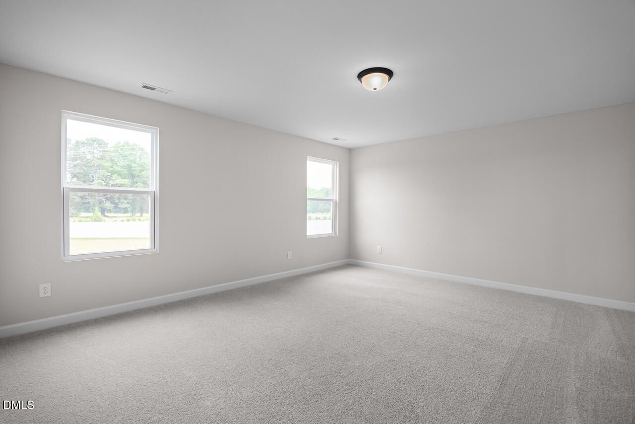 Spacious, sunlit bedroom with neutral carpet in The Willow B floor plan at Woodland Crossing, Zebulon, North Carolina.