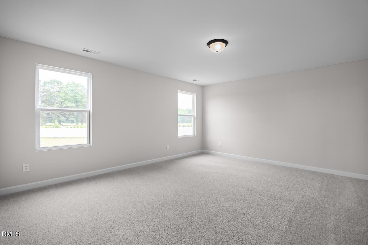 Spacious, sunlit bedroom with neutral carpet in The Willow B floor plan at Woodland Crossing, Zebulon, North Carolina.