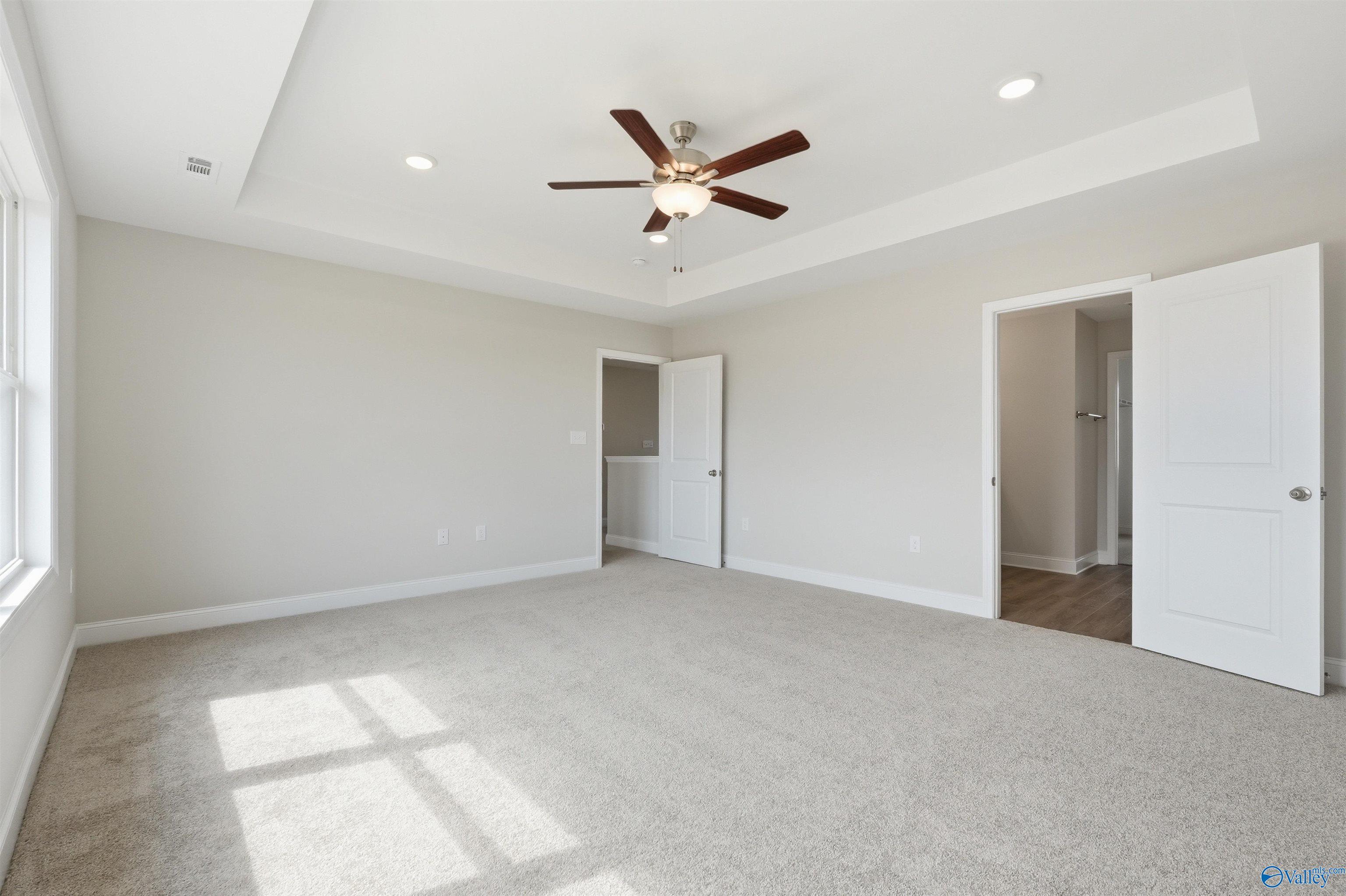 Spacious bedroom with tray ceiling and ceiling fan in The Shelby D floor plan by Davidson Homes in Evergreen Mill, Madison.