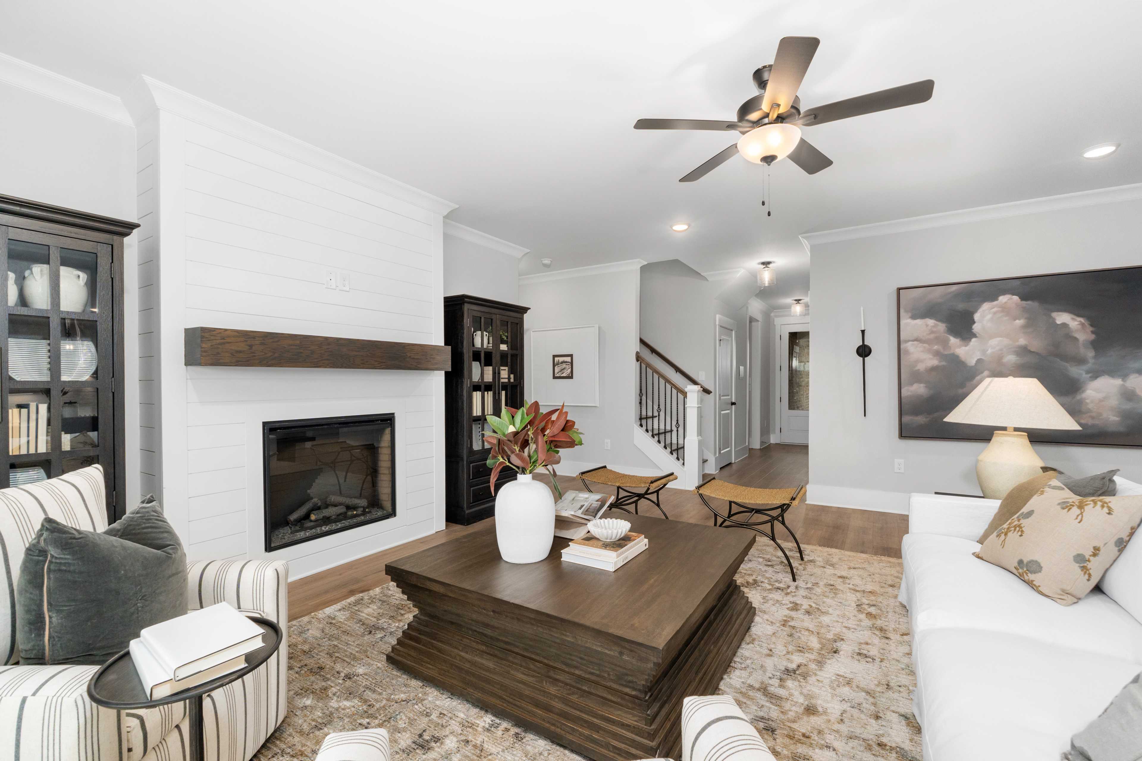 Cozy living room at Kendall Farms in Toney Alabama featuring white shiplap walls, gas fireplace, ceiling fan, and plush sectional sofa