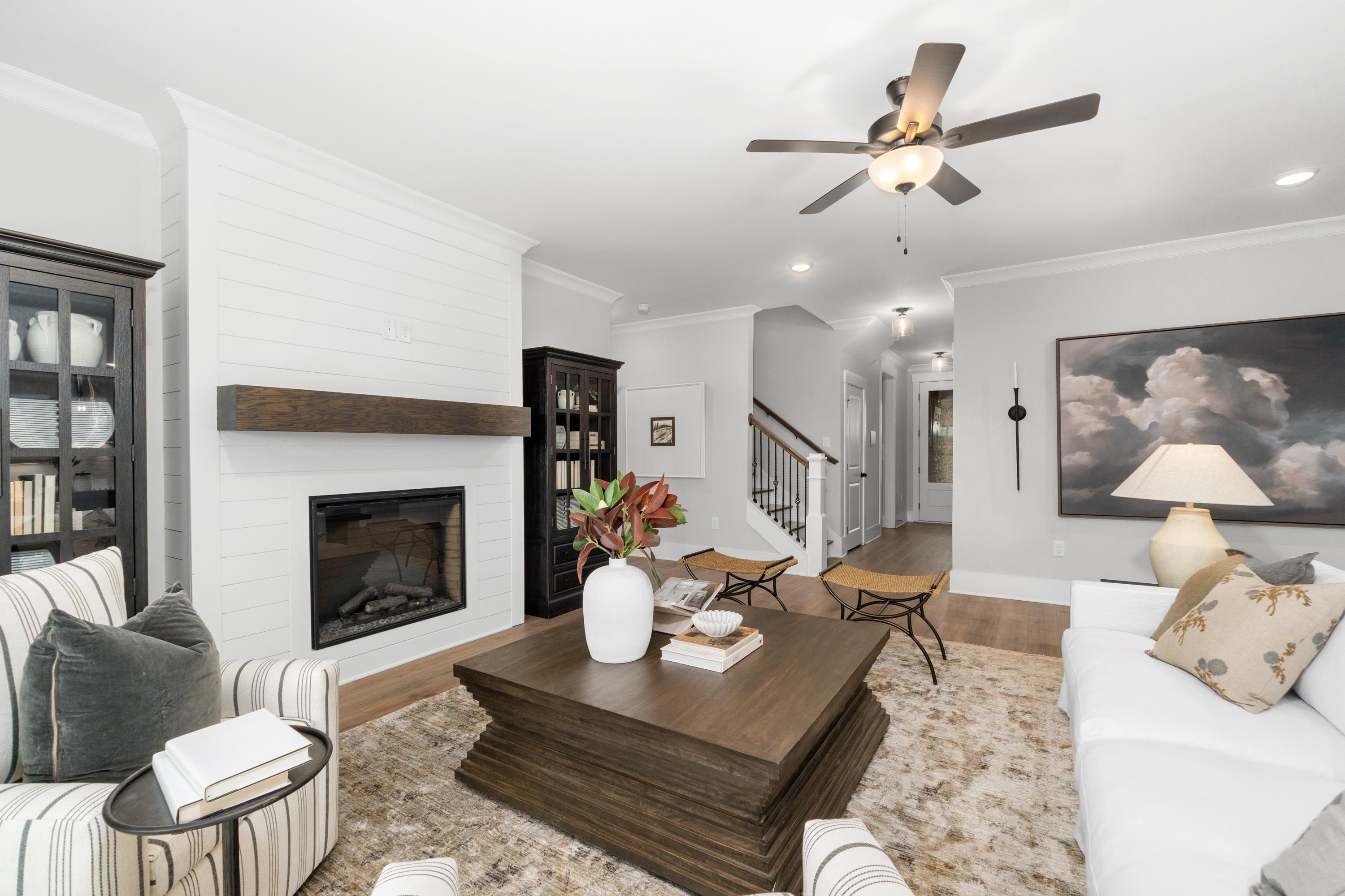 Cozy living room at Kendall Farms in Toney Alabama featuring white shiplap walls, gas fireplace, ceiling fan, and plush sectional sofa