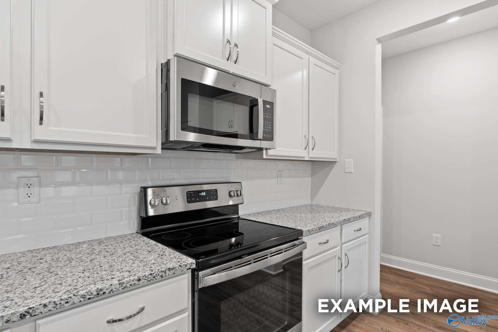 Modern kitchen featuring white shaker cabinets, granite countertops, subway tile backsplash, and stainless steel appliances in The Cumberland by Davidson Homes, Decatur, AL