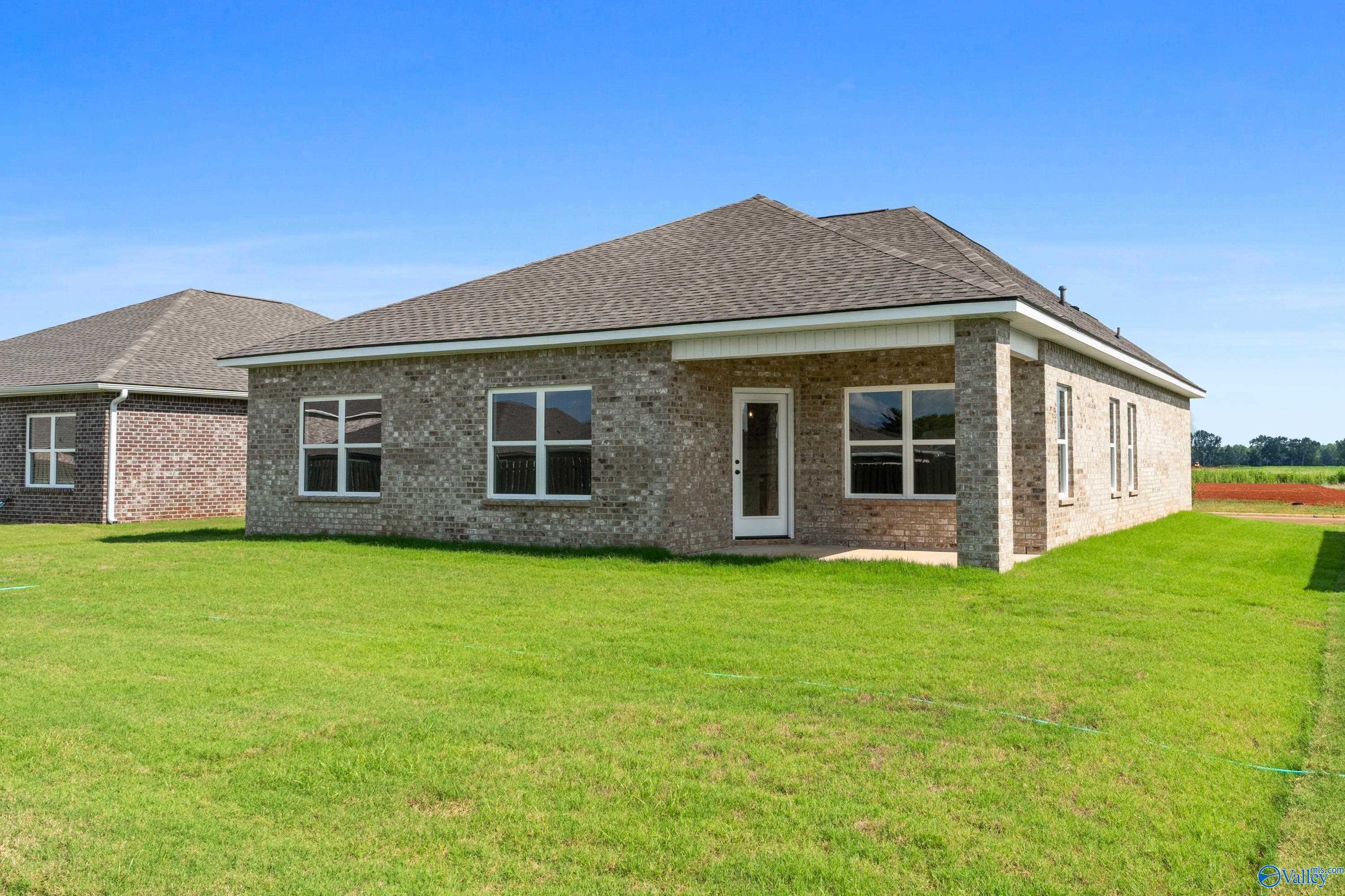 Brick single-story home with gabled roof, large windows, and 2-car garage on lush green lawn in Clearview, Hazel Green, Alabama