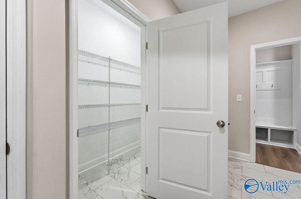 Open walk-in pantry with wire shelving next to mudroom bench and hooks in Davidson Homes The Harrison, Cain Park Hartselle Alabama