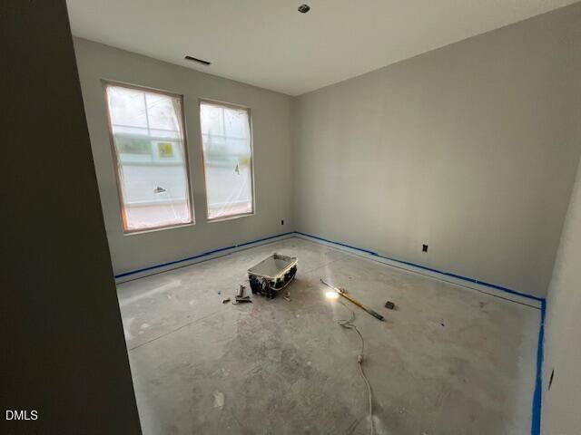 Unfinished bedroom with two windows and bare concrete floor under construction in The Daphne C by Davidson Homes, Lillington, NC