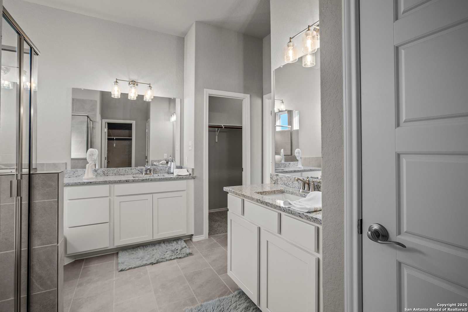 Spacious master bathroom featuring double vanity, granite counters, mirrors, and walk-in closet in Davidson Homes The Collin B, Seguin, Texas