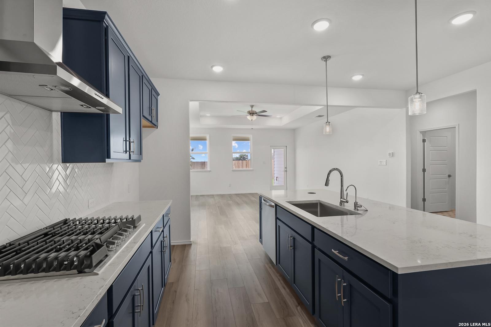 Modern navy kitchen with quartz island, subway tile backsplash, gas range, open to living area in Davidson Homes The Glenwood E, Elmendorf TX