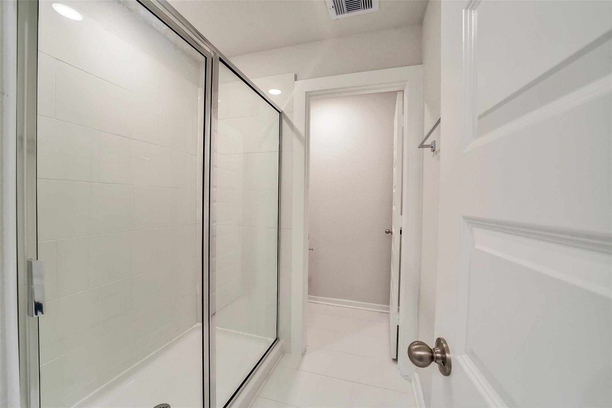 Elegant master bathroom featuring frameless glass shower enclosure and white subway tile walls in Davidson Homes The Trinity F, Magnolia, Texas