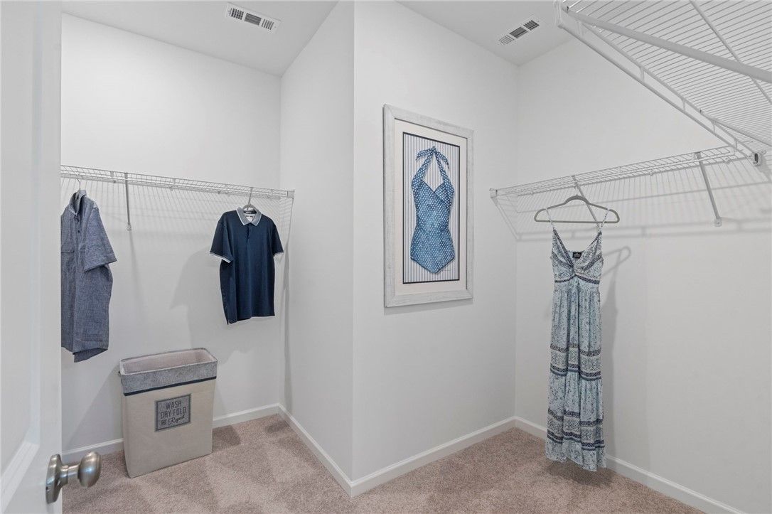 Spacious walk-in closet with hanging shirts, dresses, laundry basket in Davidson Homes The Phoenix B, Opelika, Alabama