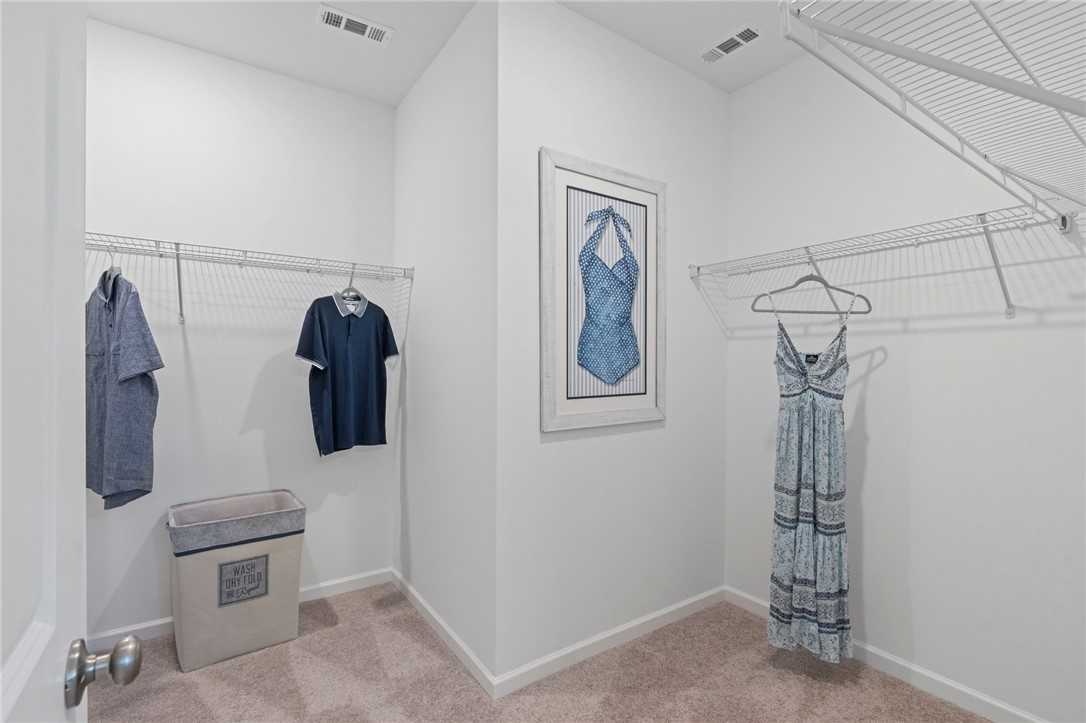 Spacious walk-in closet with hanging shirts, dresses, laundry basket in Davidson Homes The Phoenix B, Opelika, Alabama
