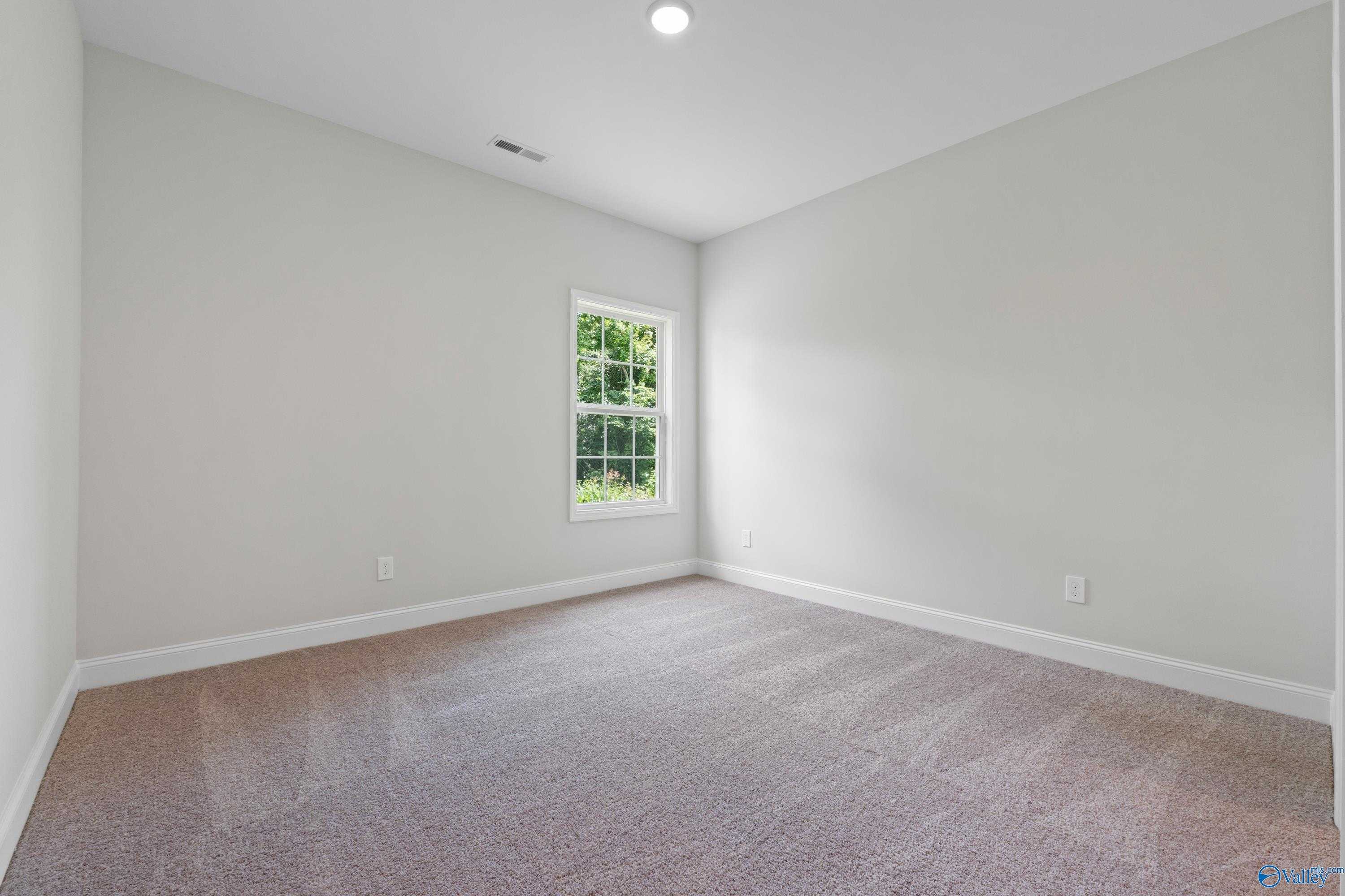 Bright secondary bedroom with beige carpet, gray walls, and window overlooking trees in The Kirkland with Bonus, Harvest, AL