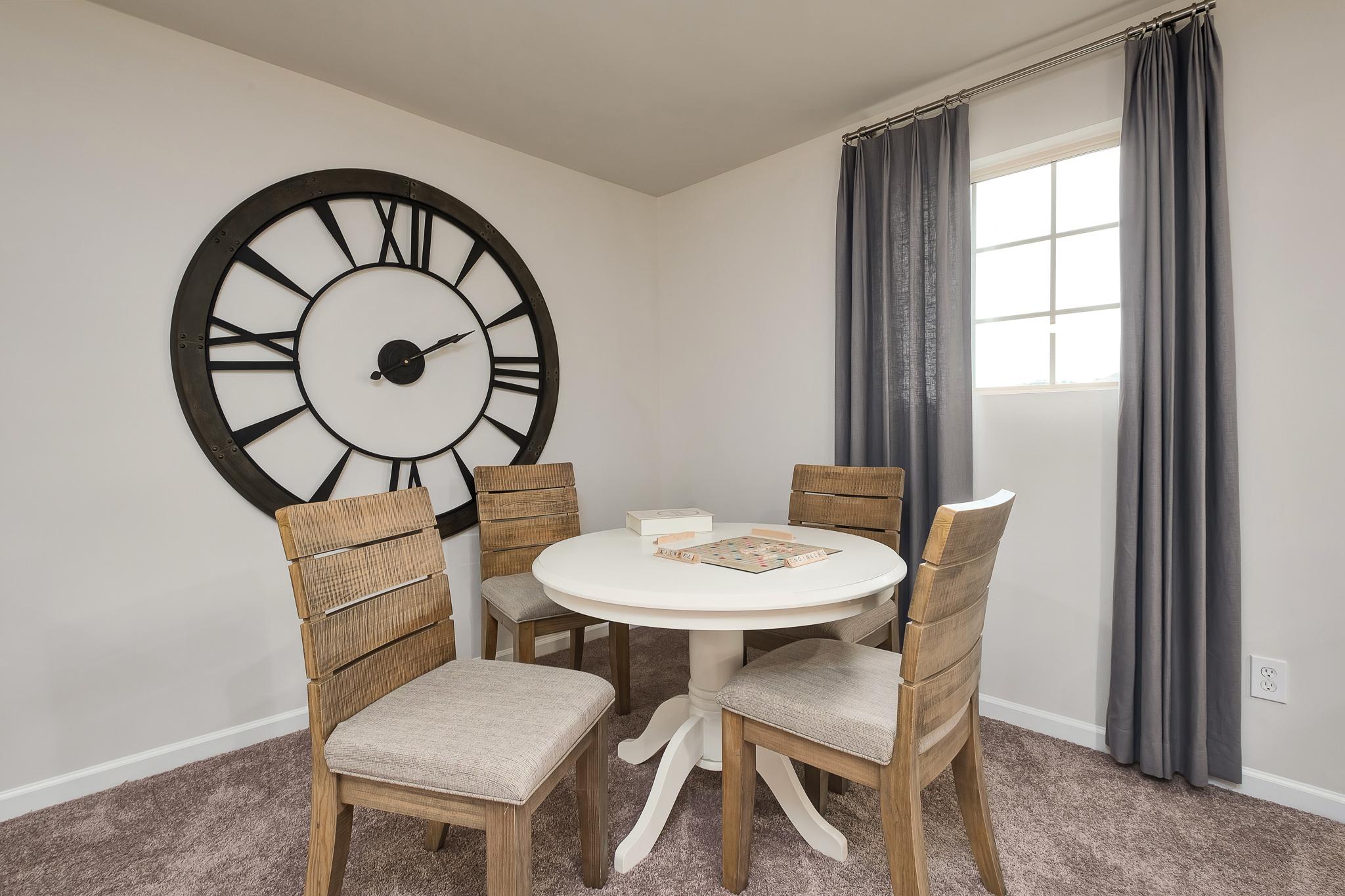 Cozy dining nook at The Reserve at Overton in Hampton Cove, Alabama with round table, wooden chairs, and large wall clock
