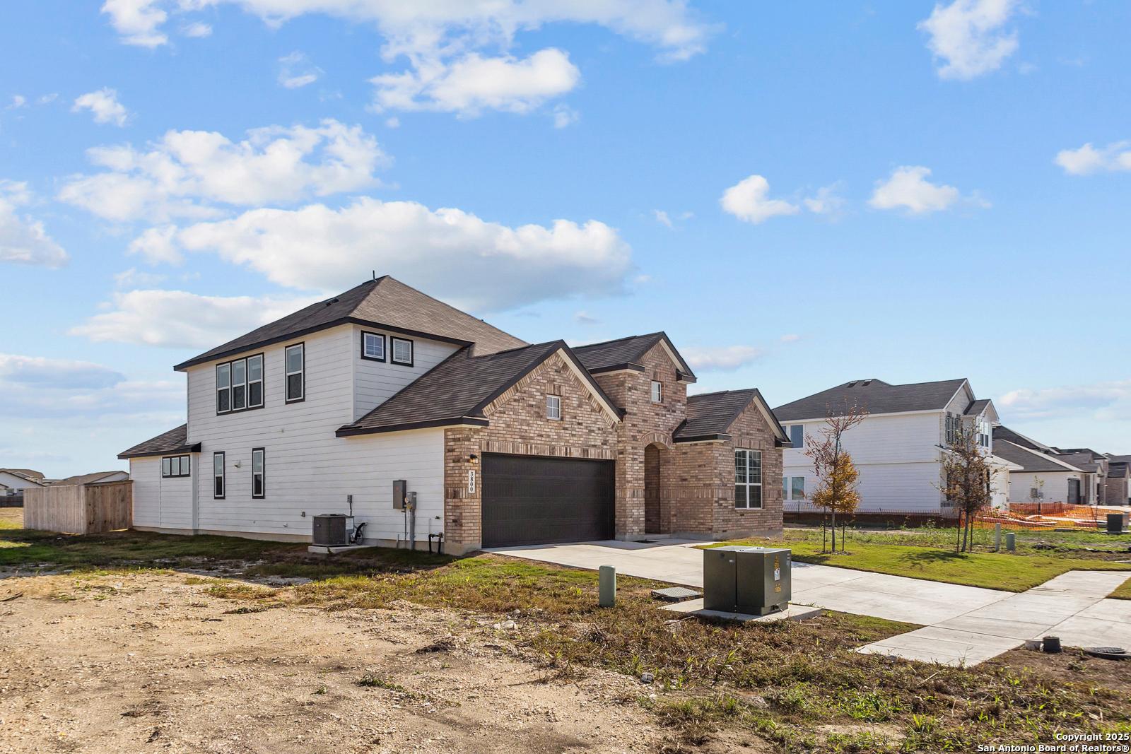 Modern 1-story Collin B home exterior with white siding, brick accents, 2-car garage in Hannah Heights, Seguin, Texas