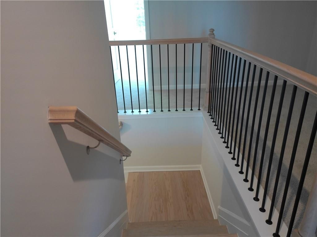 Elegant oak staircase with black iron balusters and wooden handrail in 2-story The Marion C home, Winder, Georgia