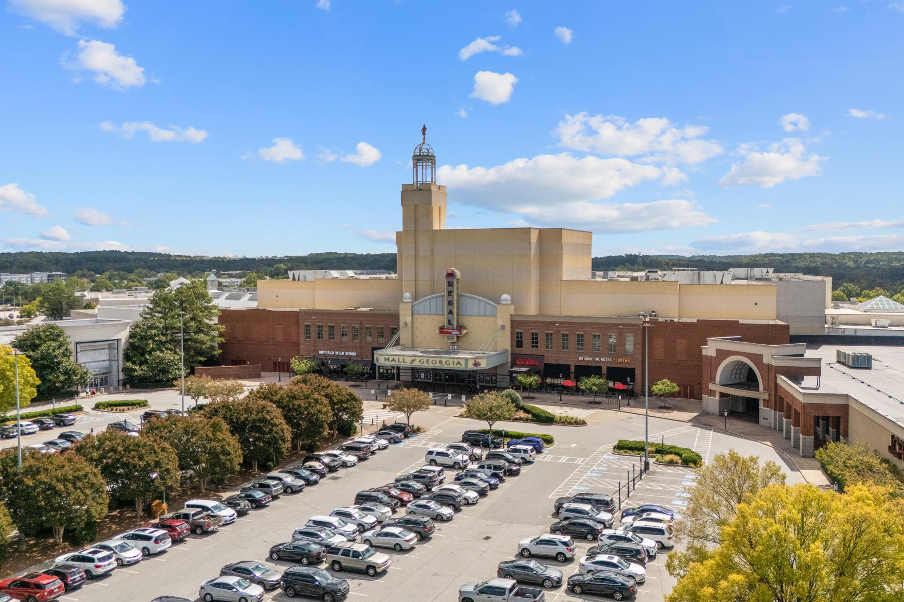 Aerial view of modern theater marquee and retail complex with parking lots near Melody Lakeside Estates in Buford Georgia