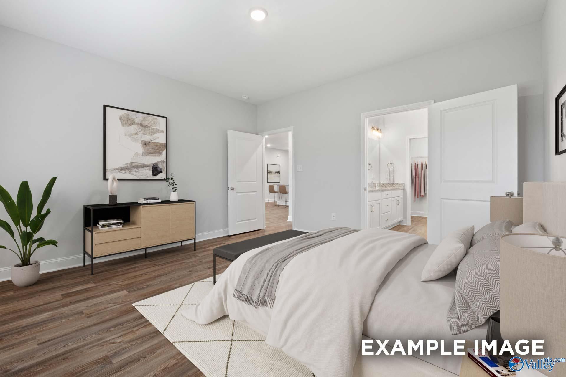 Elegant master bedroom with king bed, neutral decor, potted plants, and open en-suite bath in Davidson Homes The Cumberland, Decatur AL