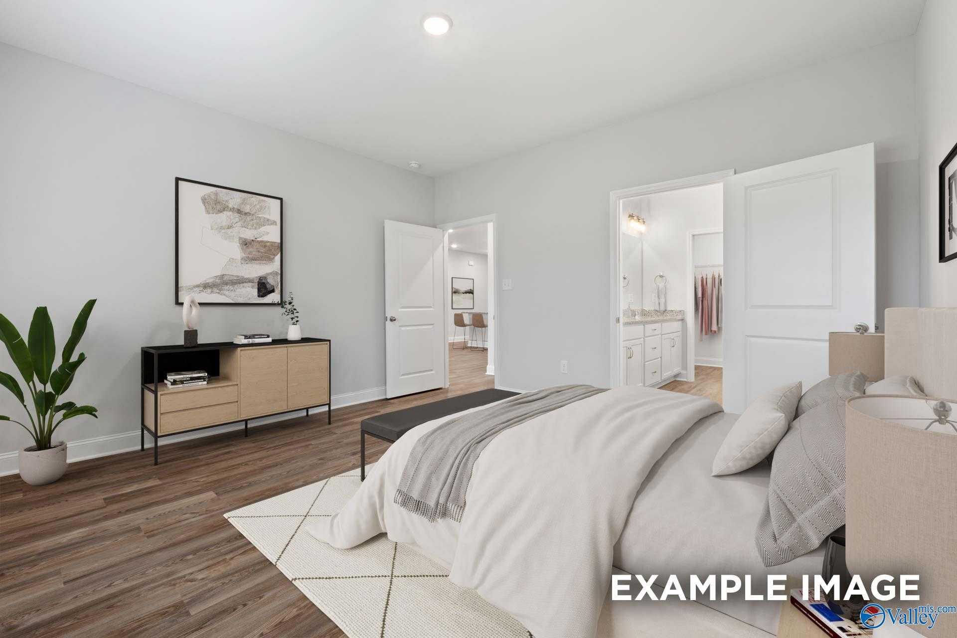 Elegant master bedroom with king bed, neutral decor, potted plants, and open en-suite bath in Davidson Homes The Cumberland, Decatur AL