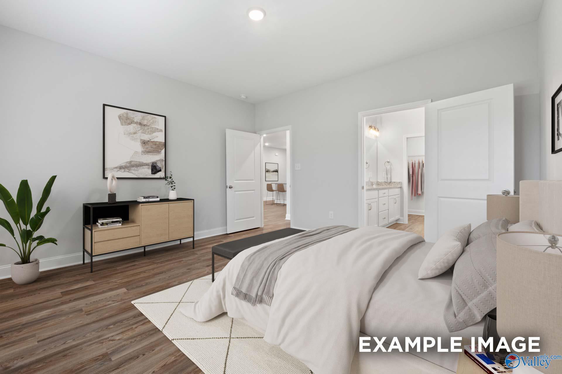 Serene master bedroom with plush king bed, neutral tones, wood floors, potted plant, and en-suite bath in Davidson Homes The Cumberland, Decatur AL