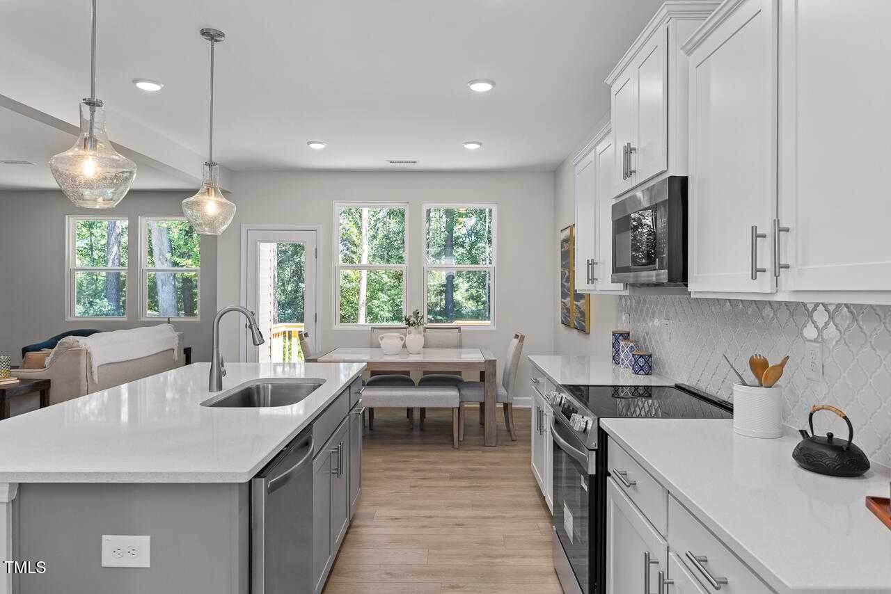 Modern open-concept kitchen with white cabinets, granite island, stainless appliances in Davidson Homes The Willow C, Lillington, NC