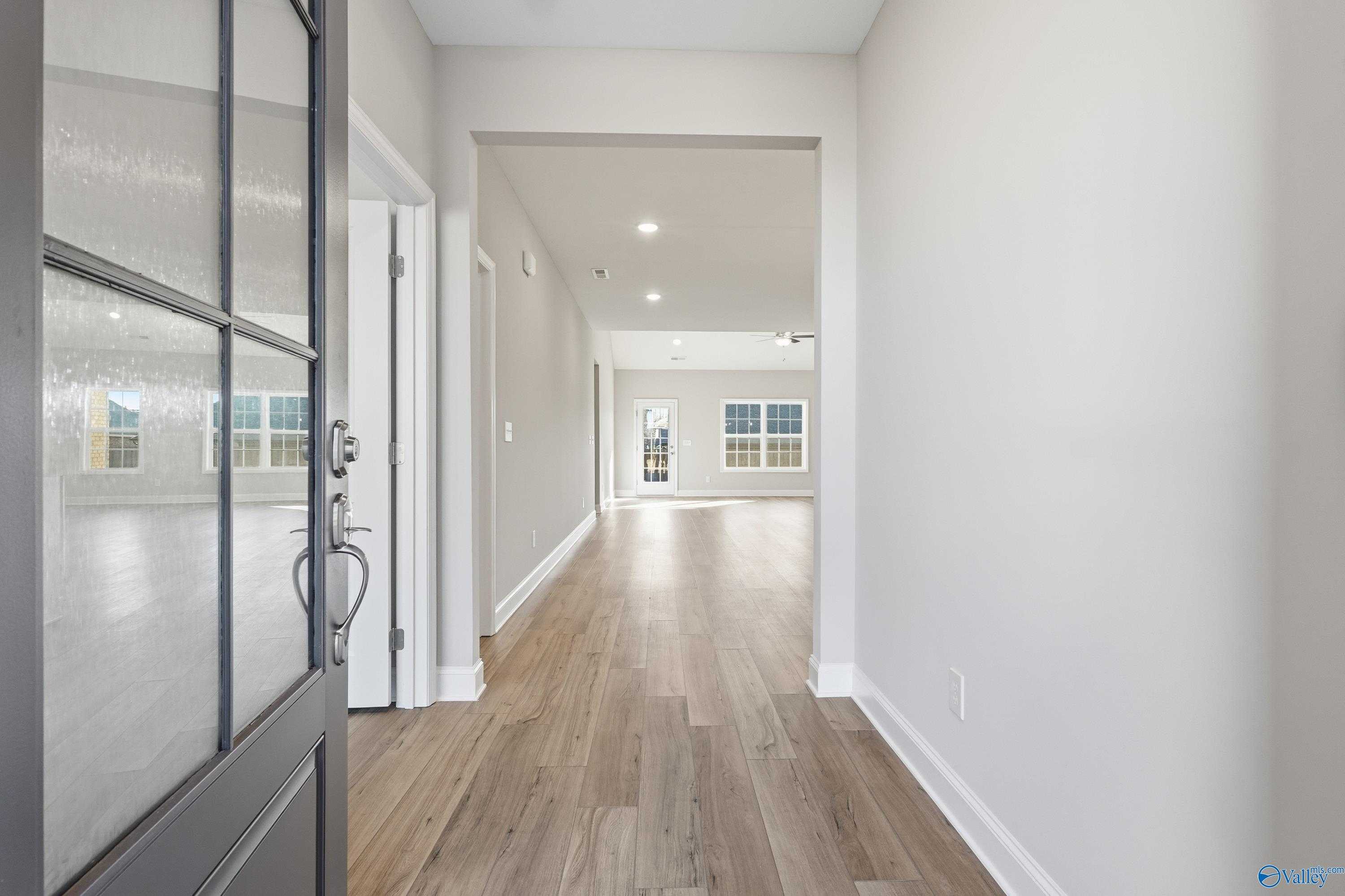 Welcoming foyer with glass-paneled front door, hardwood floors, and open hallway in The Lanier 4-bedroom home, Toney, Alabama