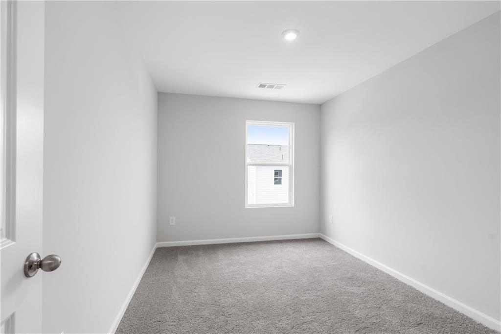 Empty bedroom featuring light gray walls, gray carpet, window view, and recessed lighting in Davidson Homes The Monroe B, Emerson, GA