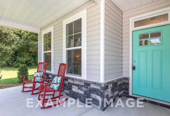 Davidson Homes the Chestnut Plan Front Porch with stone accents, red rocking chairs and teal colored front door