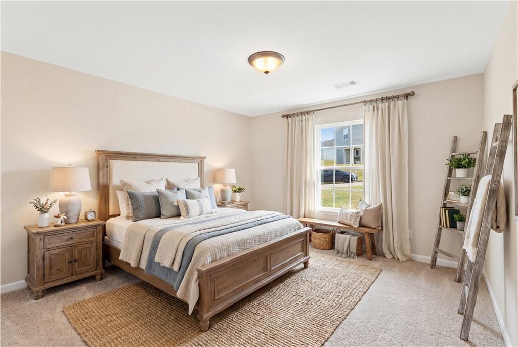 Cozy bedroom with wooden bed, neutral tones, ladder shelf plants, and lawn view in Davidson Homes The Washington, Phenix City, Alabama
