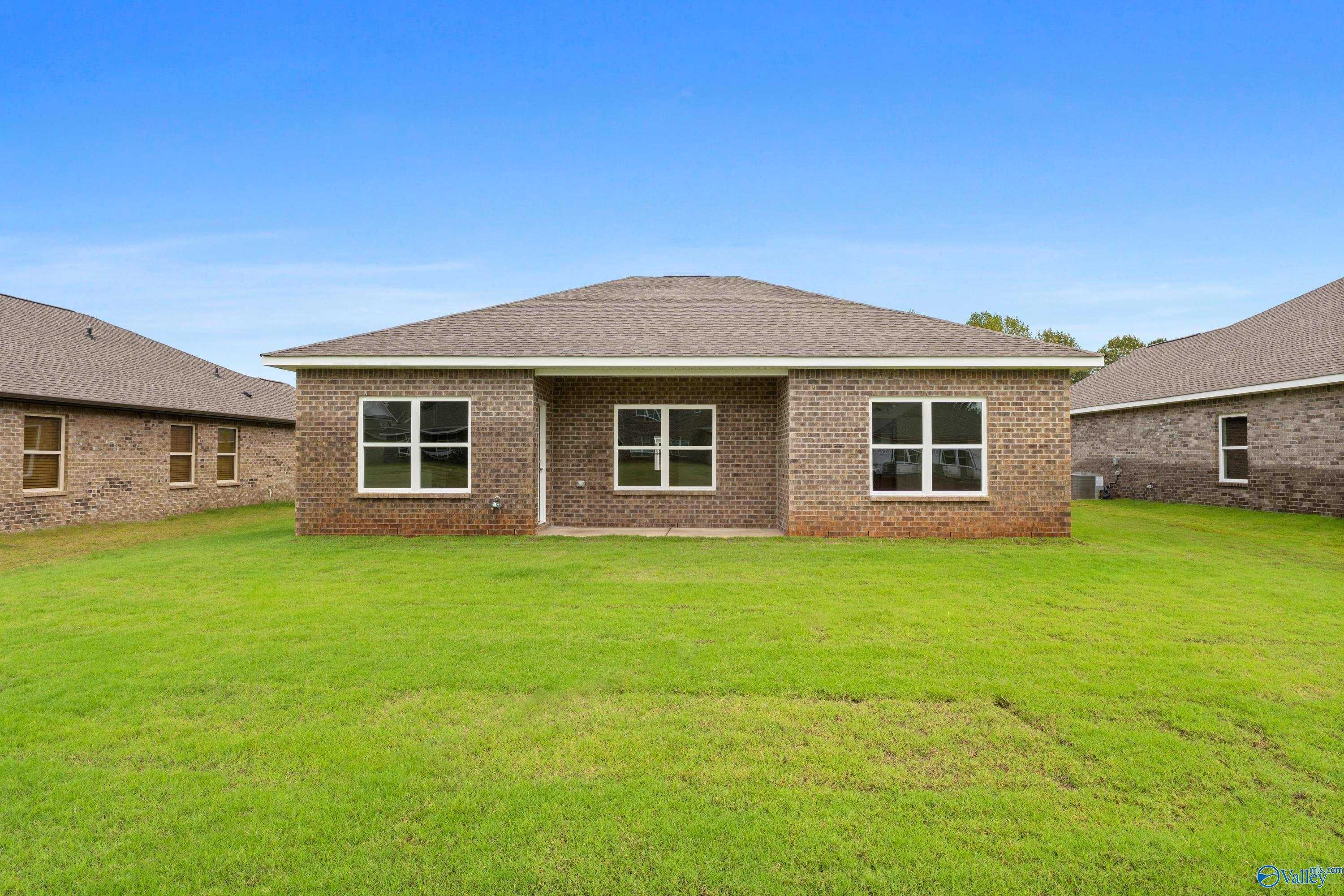 Single-story brick home exterior with gabled roof, double windows, and lush green yard in Ricketts Farm, Athens, Alabama
