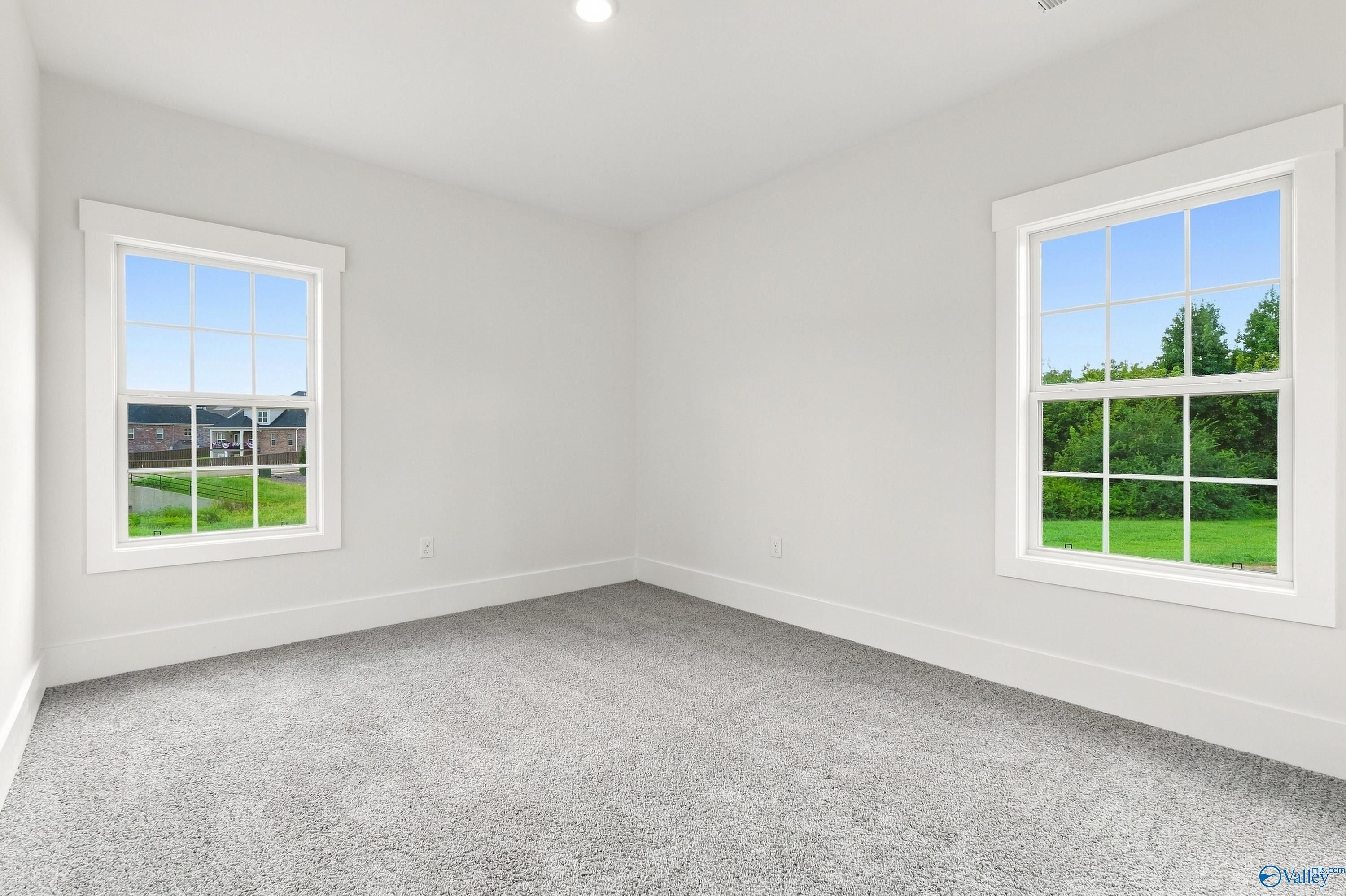 Bright empty bedroom with dual windows and gray carpet in Davidson Homes The Valencia, Riverton Preserve, Huntsville, Alabama