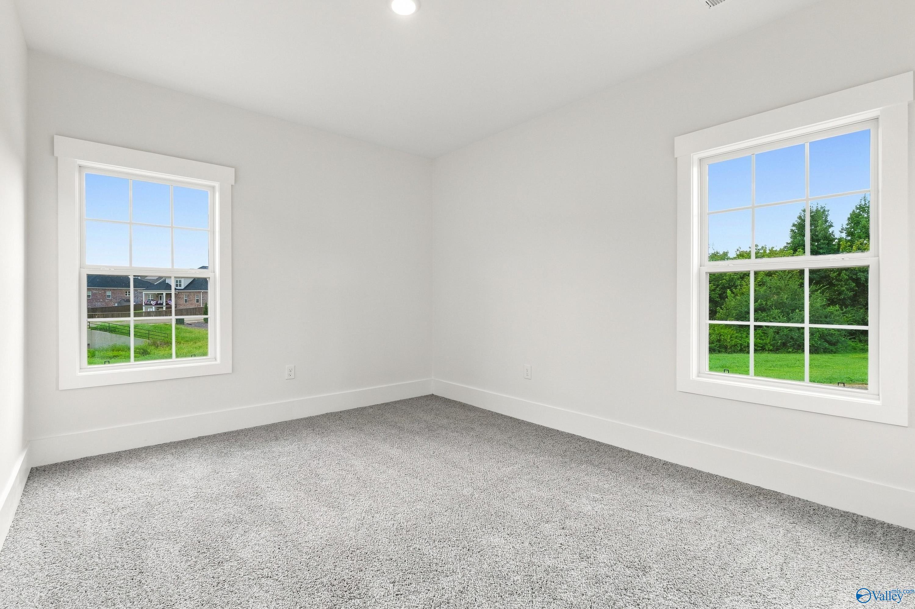 Bright empty bedroom with dual windows and gray carpet in Davidson Homes The Valencia, Riverton Preserve, Huntsville, Alabama
