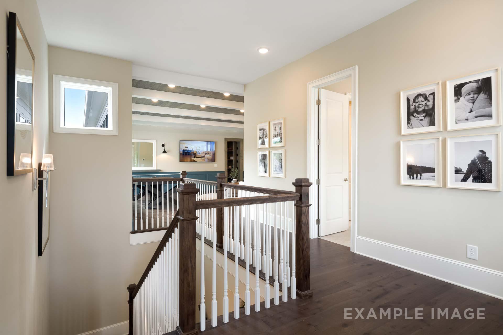 Upper floor hallway in The Seaside C home design with staircase overlook, framed photos, and hardwood floors