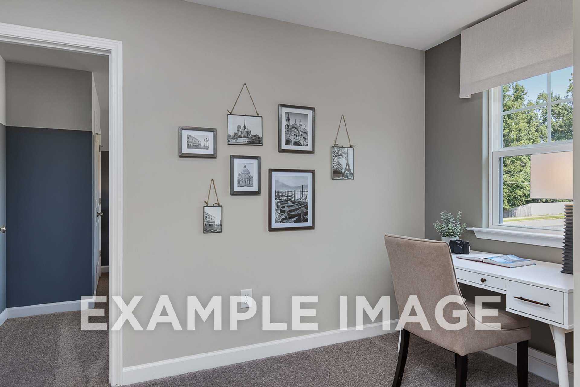 Cozy home office in The Ash E with gray walls, black-and-white photo gallery, wooden desk, potted plant, and window view