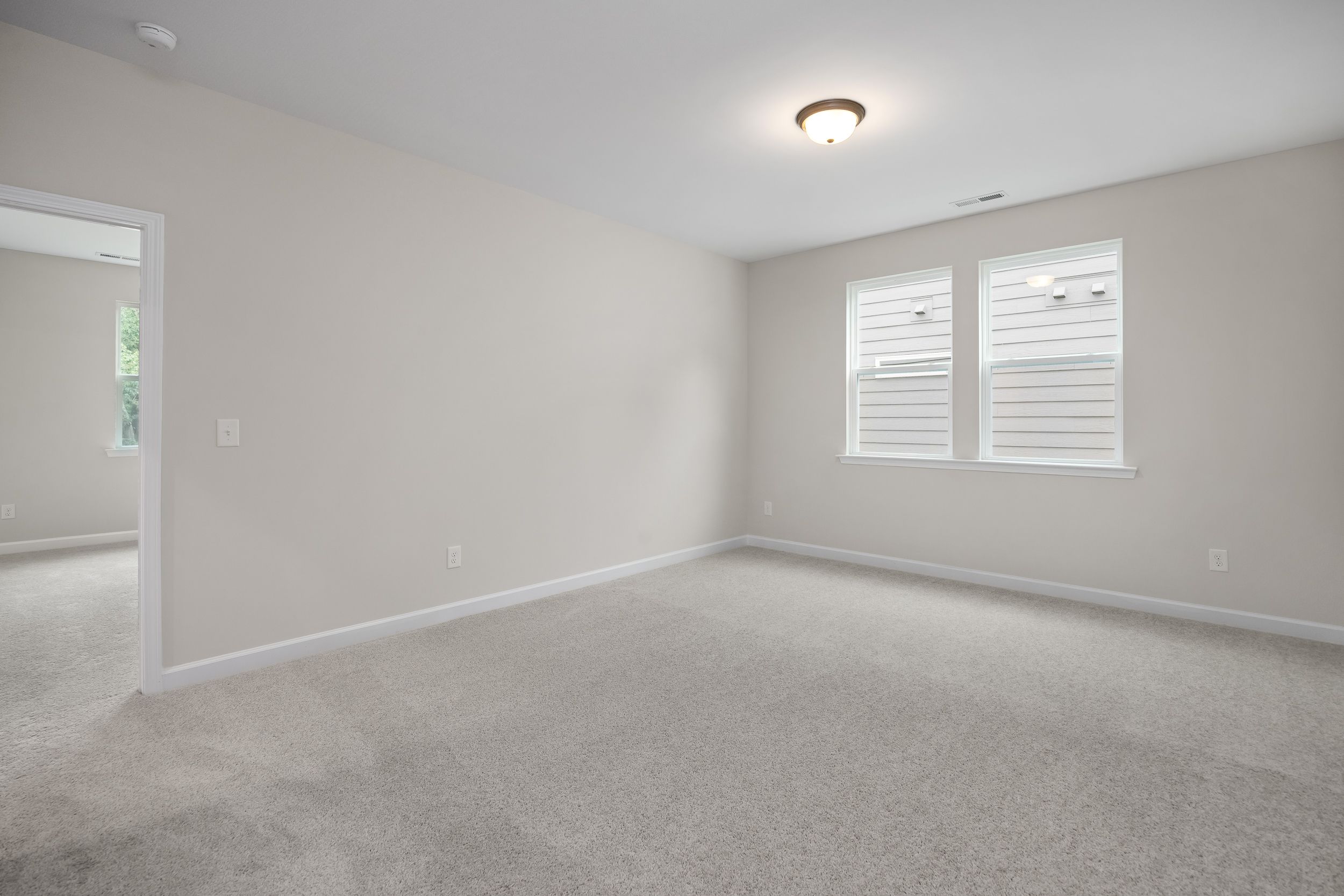 Spacious empty bedroom in The Beech A featuring beige walls, carpeted floor, large windows with blinds, and ceiling light