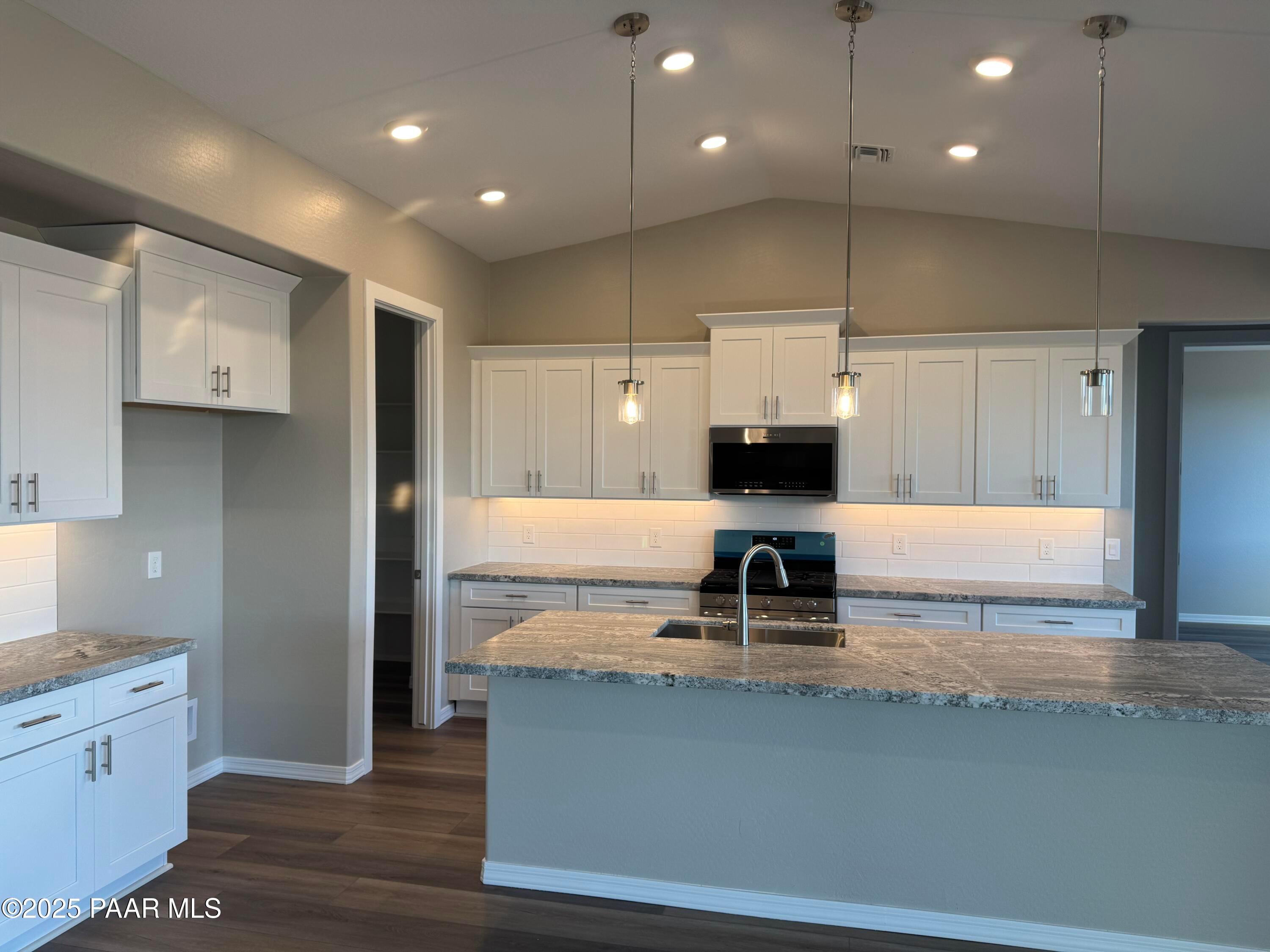 Modern kitchen with white cabinets, granite island, stainless microwave and cooktop in Davidson Homes The Monarch A, Prescott AZ