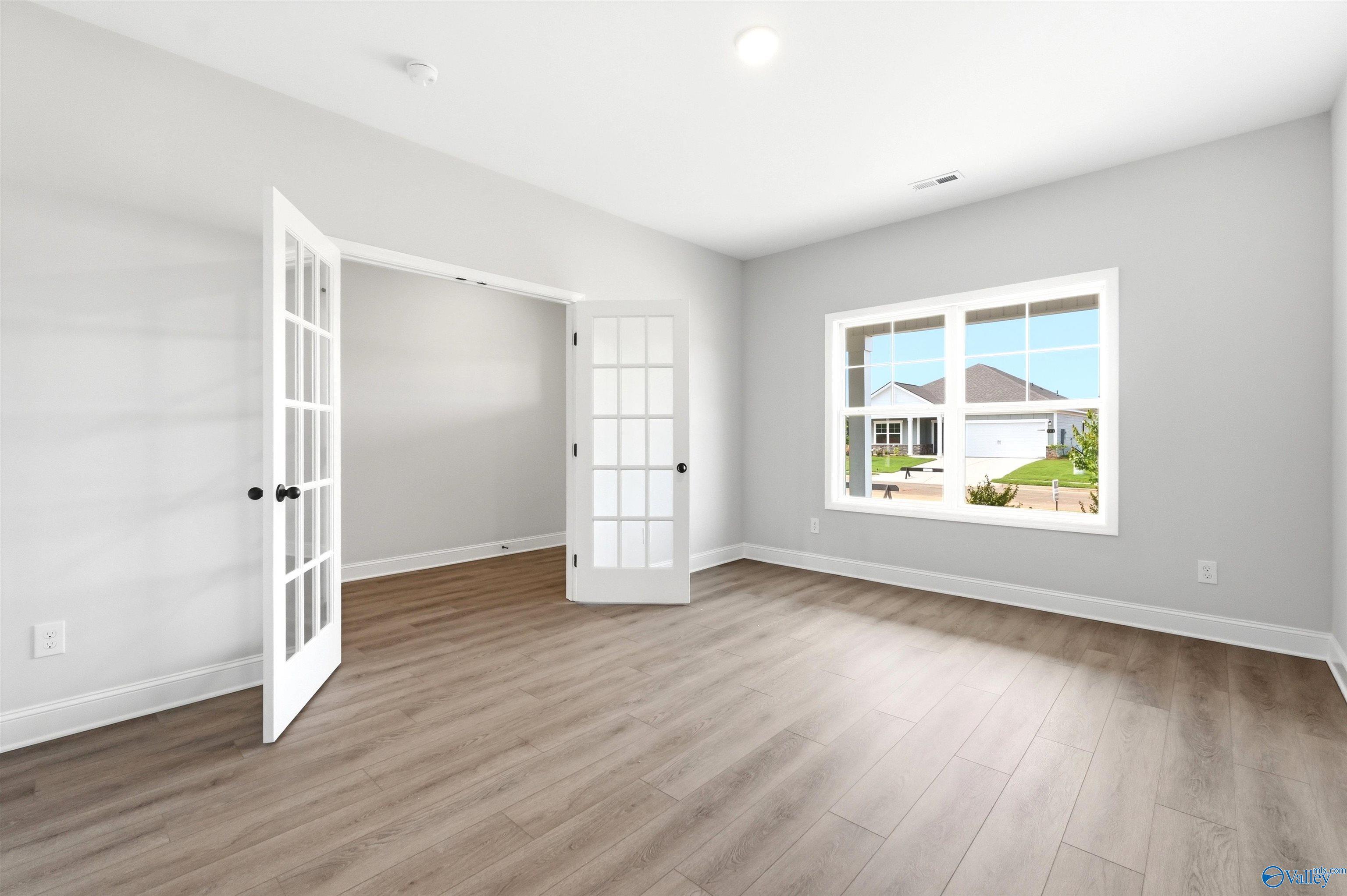Bright home office with French doors and luxury vinyl plank flooring in The Chelsea D floor plan, Berry Cove, Alabama.