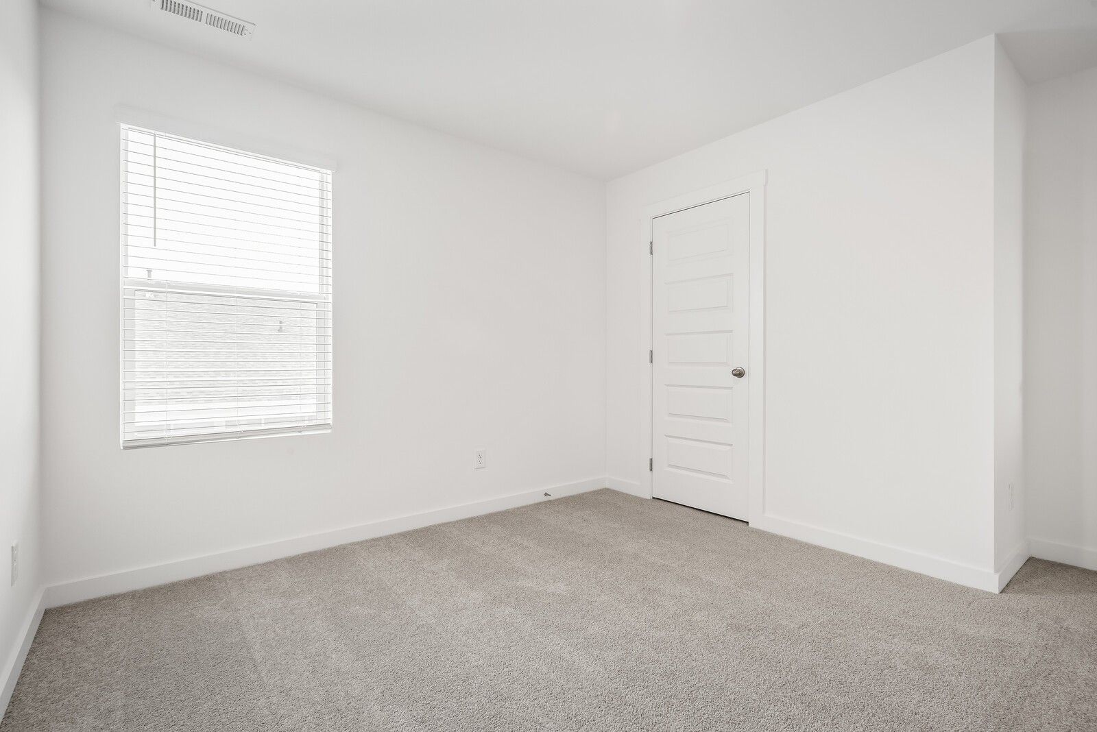 Bright secondary bedroom with white walls, window blinds, white door, and beige carpet in Davidson Homes The Gordon C, White House, TN