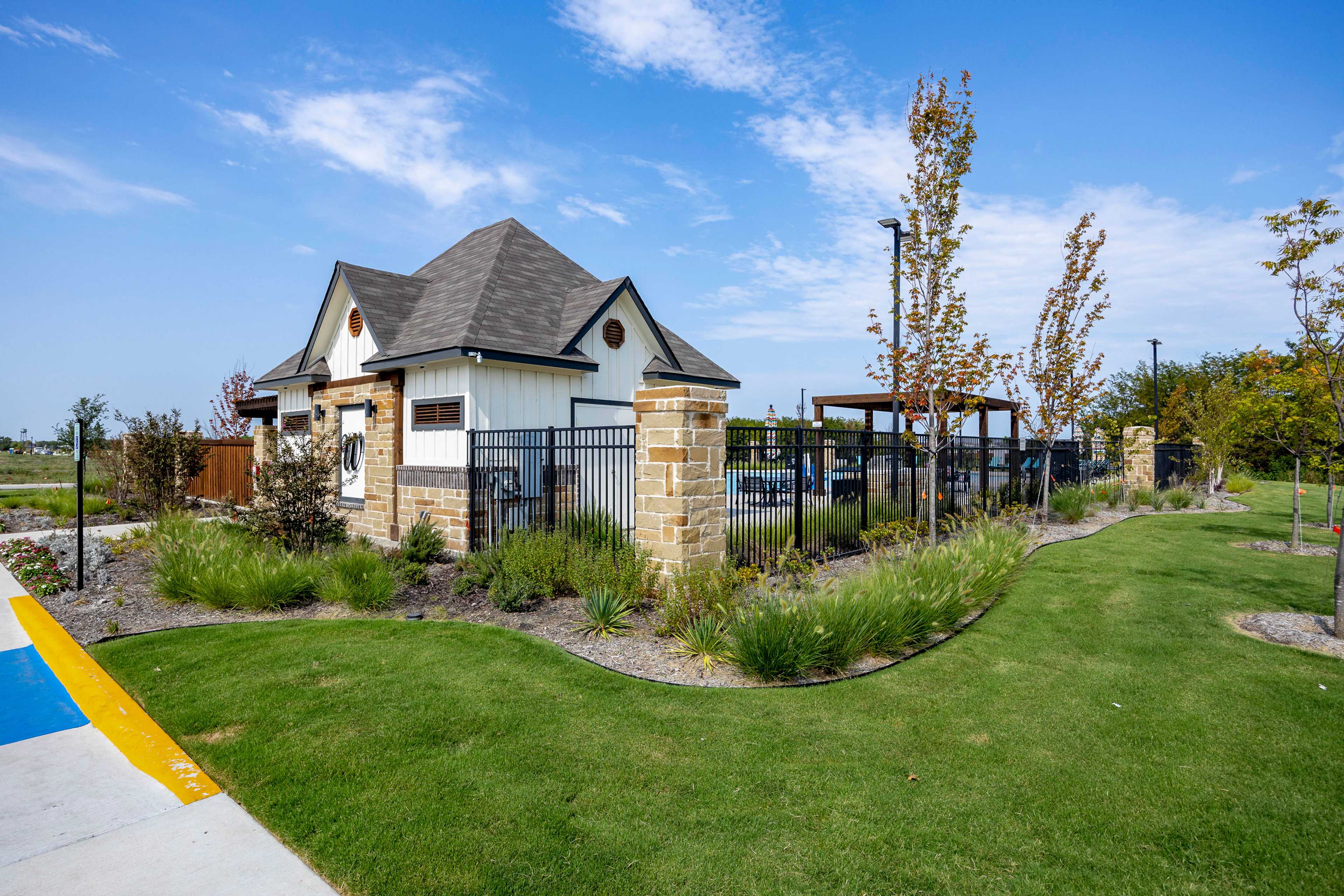 Cabana and resort-style pool at Waverly Estates in Josephine Texas with stone pillars black fencing and lush landscaping