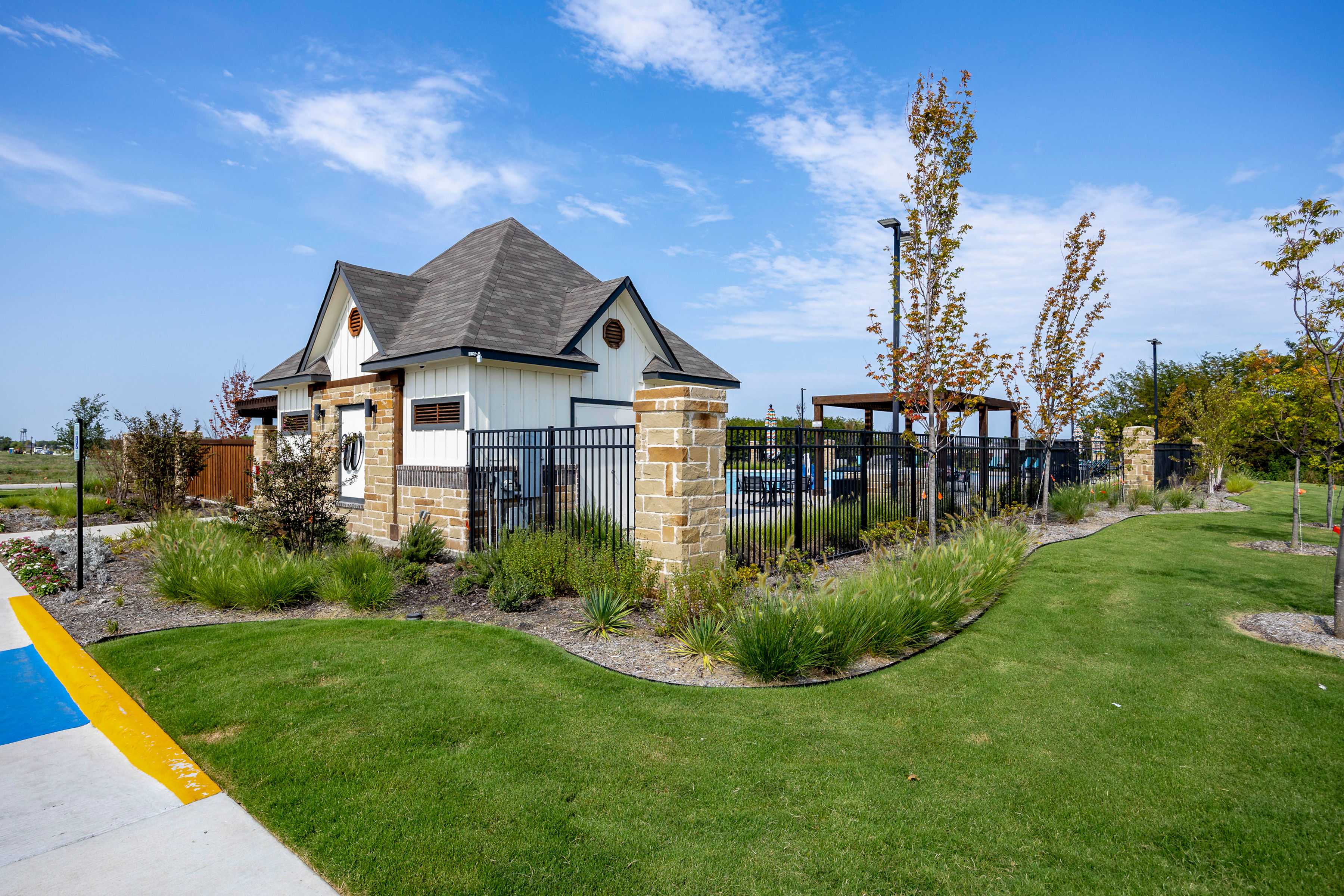 Cabana and resort-style pool at Waverly Estates in Josephine Texas with stone pillars black fencing and lush landscaping