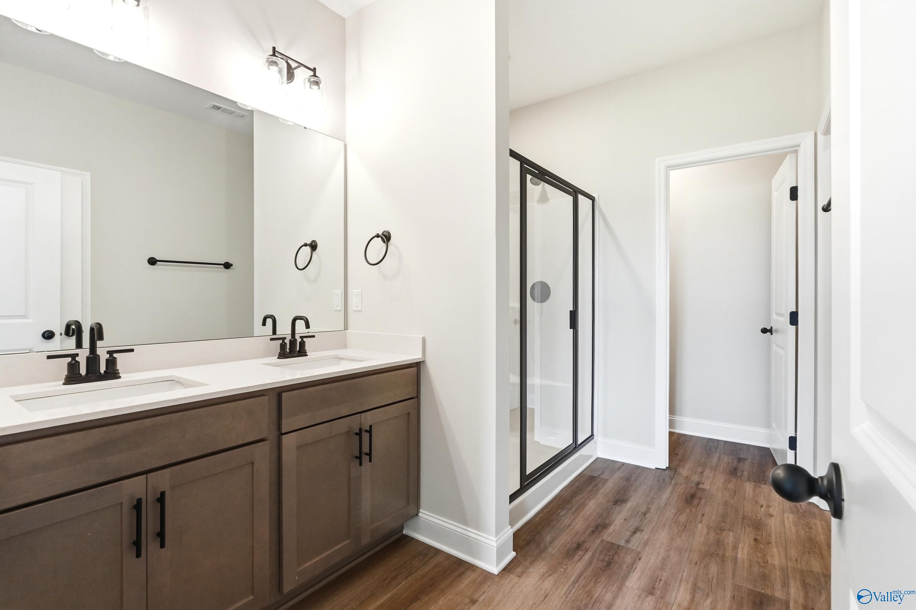 Modern master bathroom with dual vanity, dark wood cabinets, and glass shower in The Daphne floor plan, Hazel Green, AL.
