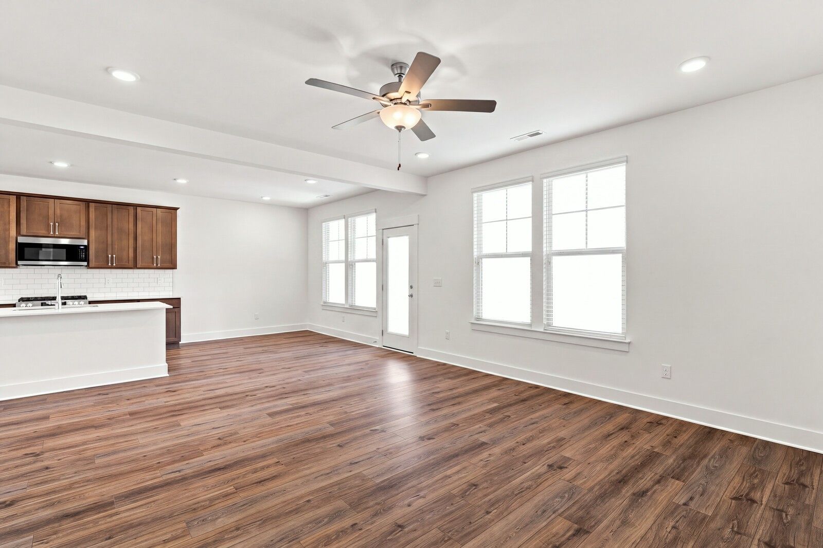 Open-concept living area with hardwood floors, ceiling fan, and wood cabinetry in Davidson Homes The Willow C, Gallatin, TN